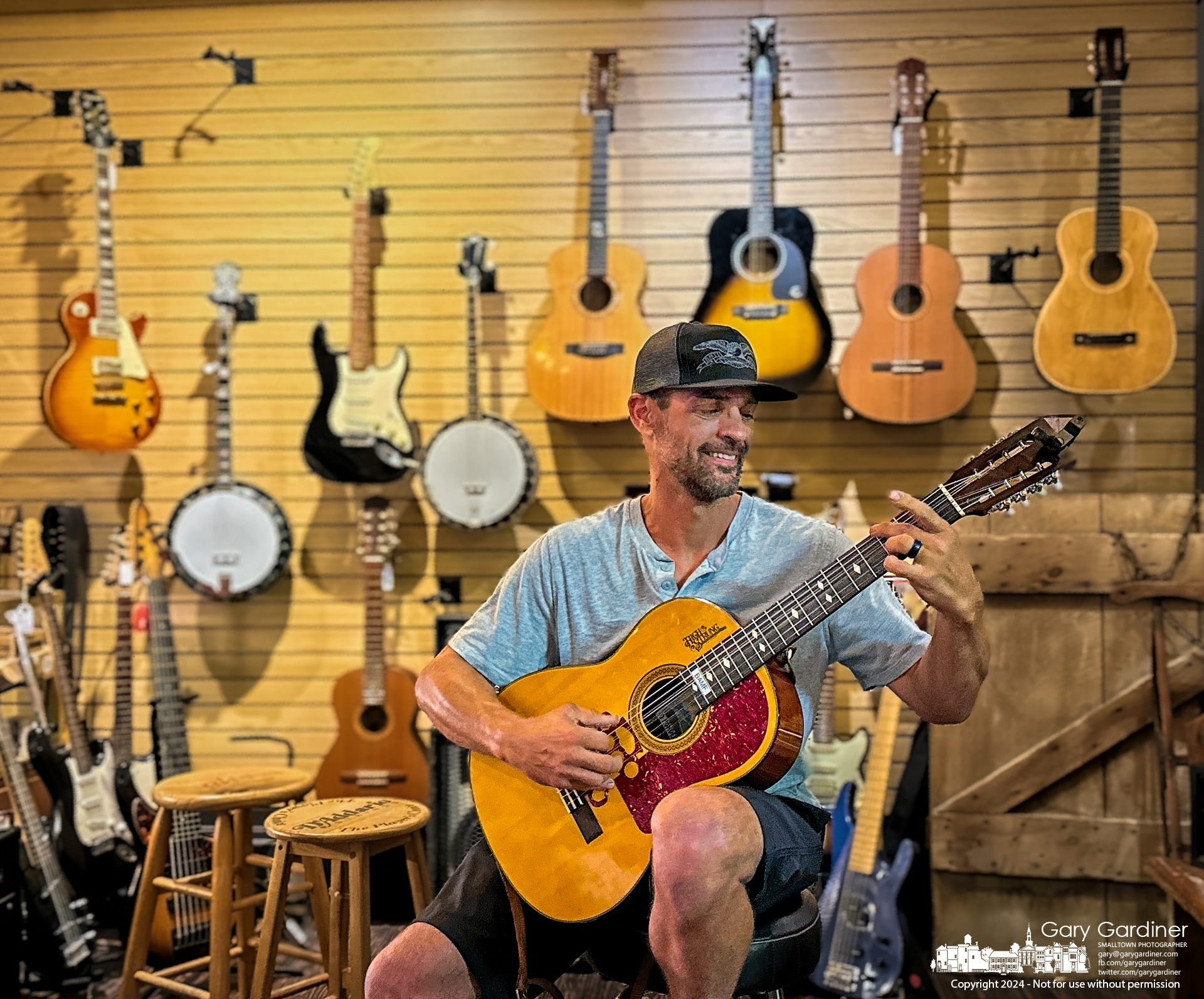 Gabriel Schick plays his homemade eight-string guitar to demonstrate its unusual sound for listeners in the Uptown Music showroom at Pure Roots in Uptown Westerville. My Final Photo for June 29, 2024.