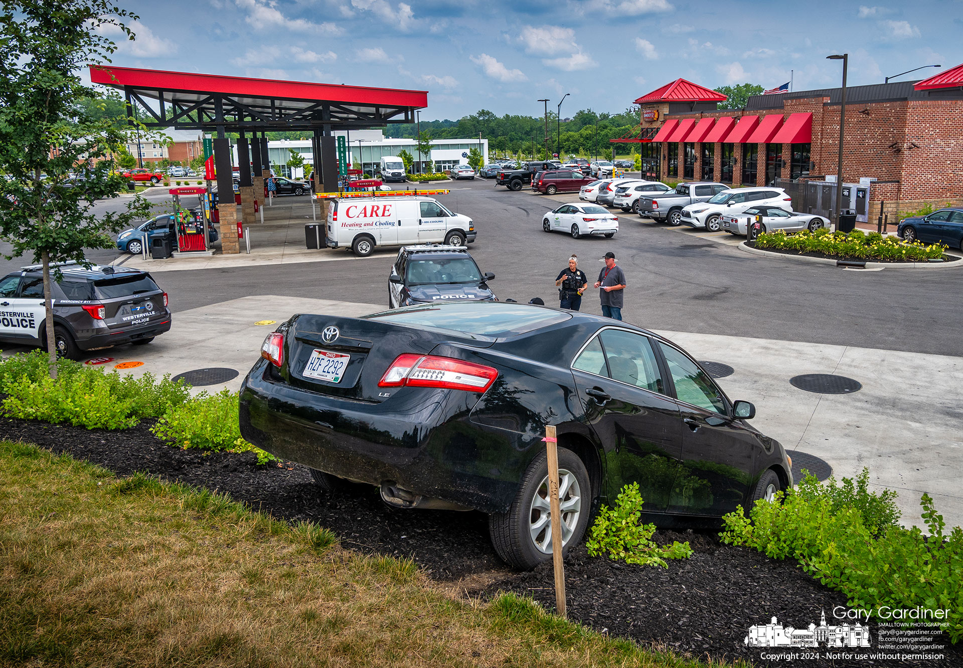 A car sits in the inclined landscaping at the edge of Sheetz on Polaris in Westerville after being driven off partially closed Old Worthington Road. My Final Photo for June 18, 2024.