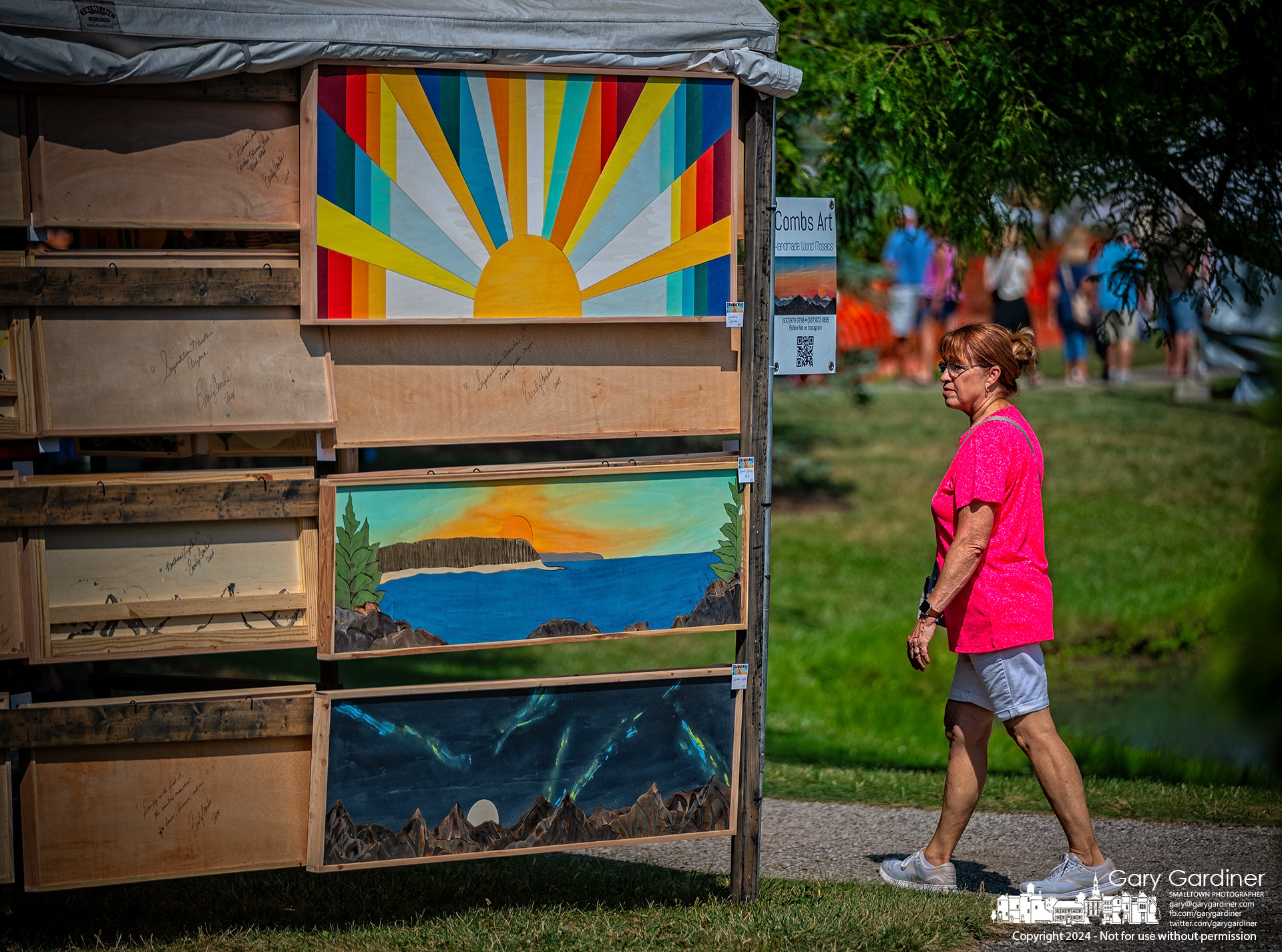 A spectator glances toward the art displayed at the first booth at the Main Street entrance to the Westerville Music and Arts Festival on Saturday morning. My Final Photo for July 13, 2024.