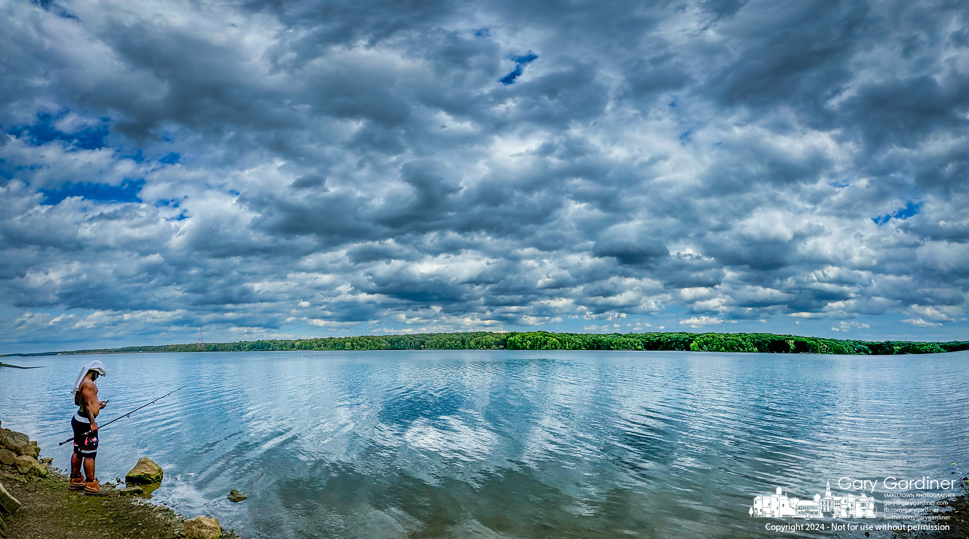 A fisherman checks his phone while waiting for his luck to change while fishing from the shore of Hoover Reservoir near Walnut Street. My Final Photo for July 16, 2024.