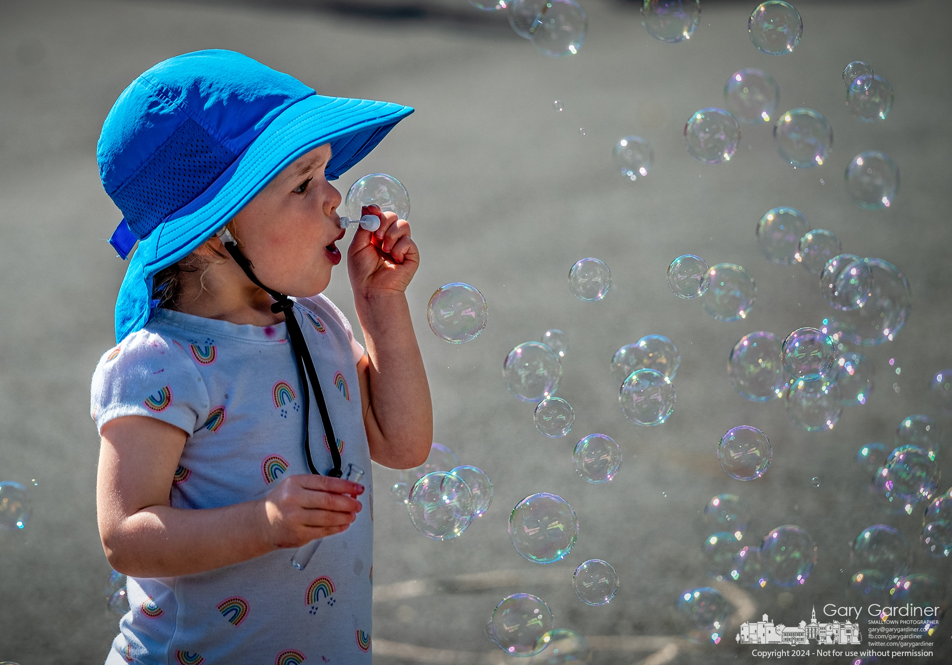 A young girl tries to blow bubbles with her small wand that matches the heavy flow of bubbles from the nearby electric bubble blowing machine at the Saturday Farmers Market in Uptown Westerville. My Final Photo for July 6, 2024.