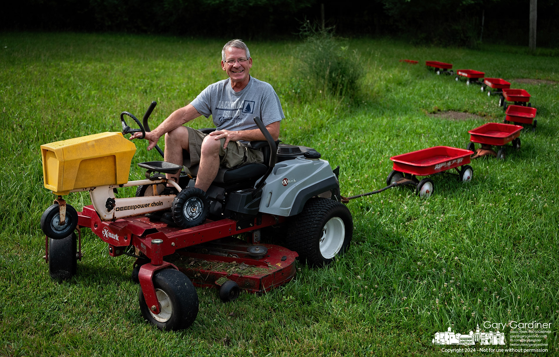 Tom Schneider removes his train of red wagons from his front yard as he changes the humorous display of cows and wagons along Tussic Road. My Final Photo for July 9, 2024.