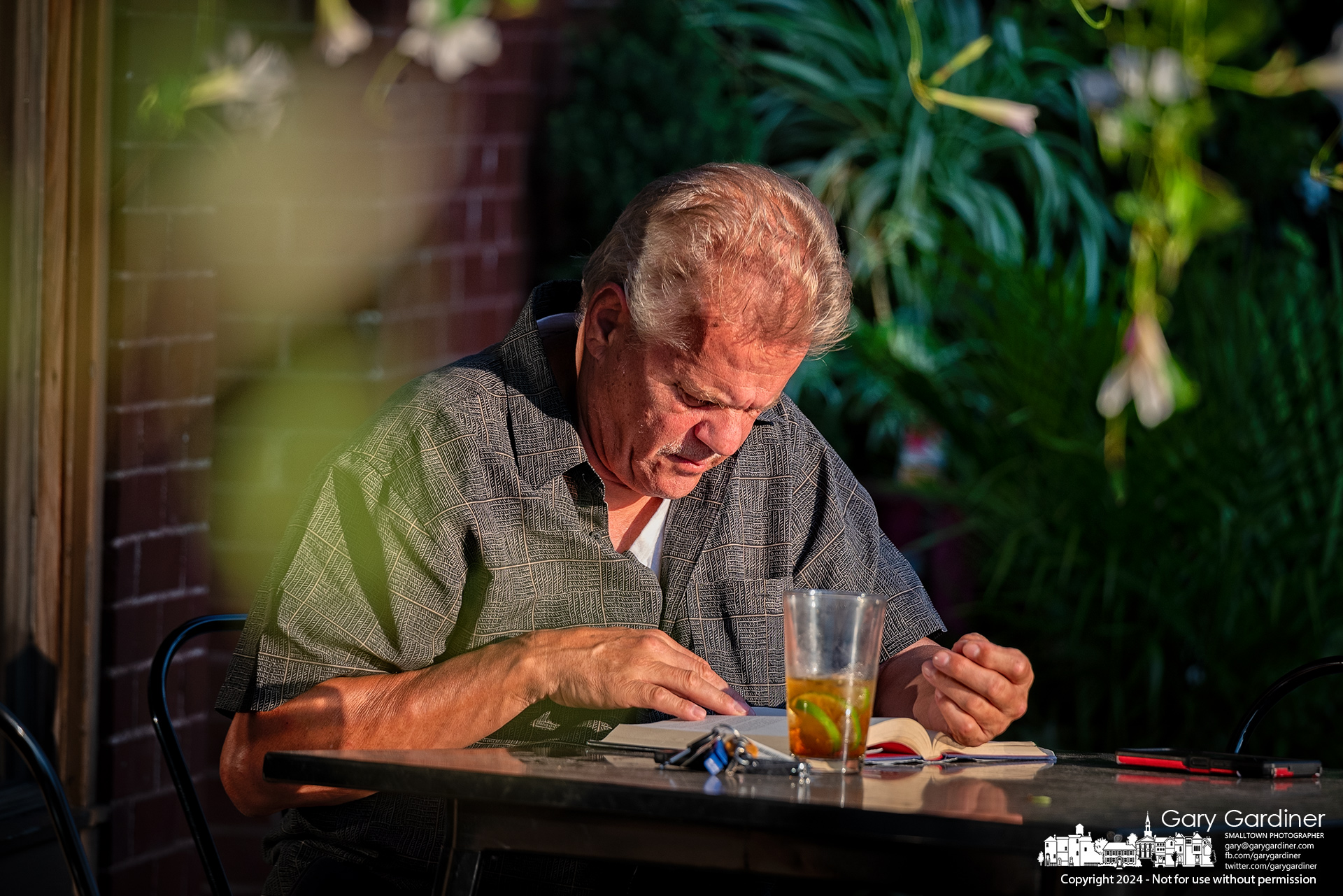 Ignacio Perez reads a book in the light from the sunset down Main Street sitting with his evening drink in front of Old Bag of Nails in Uptown Westerville. My Final Photo for August 9, 2024.