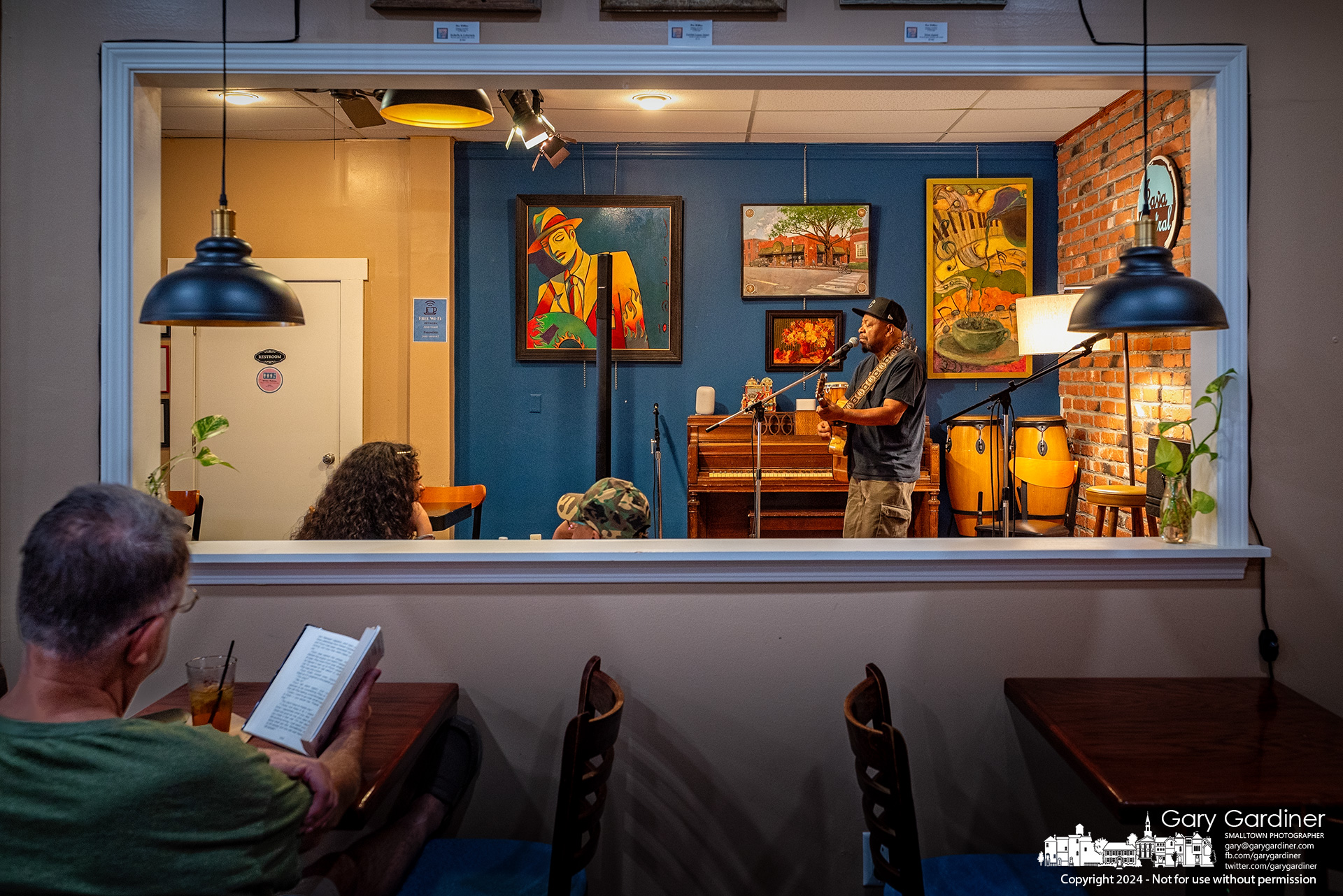 A man enjoys an iced tea and his book while listening to music during open mike night at Java Central in Uptown Westerville. My Final Photo for August 16, 2024.