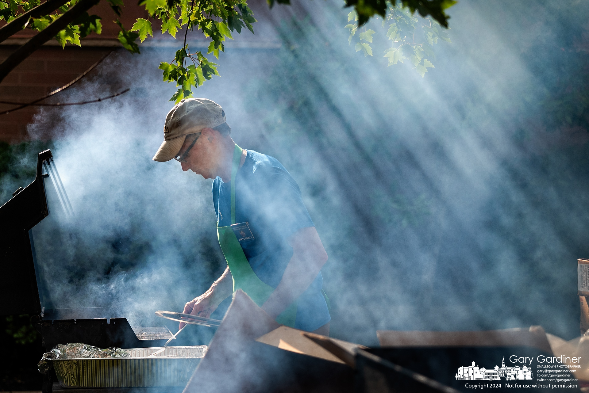 Light filters through smoke from four grills cooking for the St. Paul the Apostle Catholic Church annual picnic in the church's parking lot on North State Street in Westerville. My Final Photo for August 17, 2024.