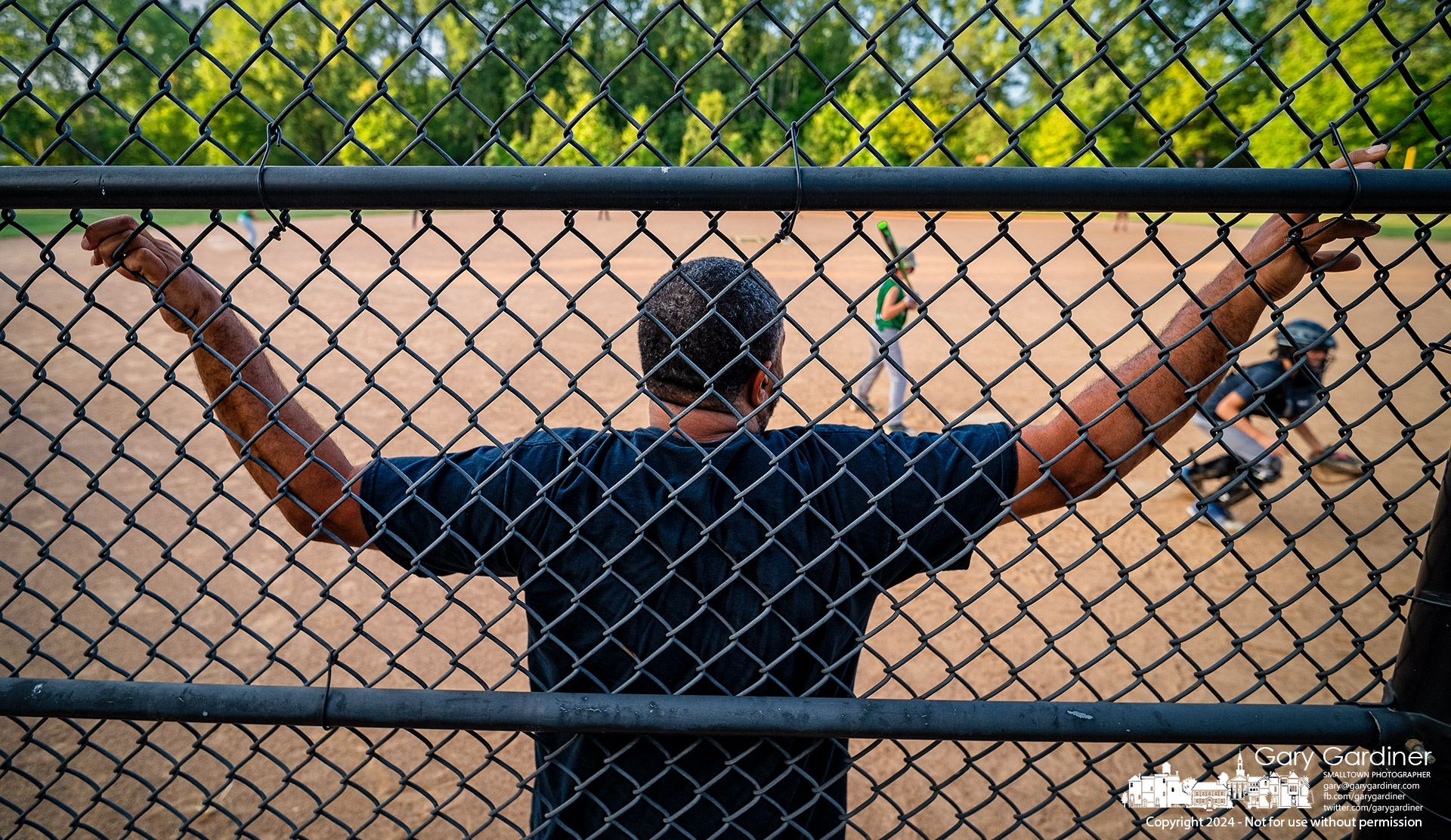 The volunteer umpire for an afternoon WYBSL scrimmage game leans against the backstop as the catcher chases a wild pitch at Huber Village Park. My Final Photo for August 22, 2024.