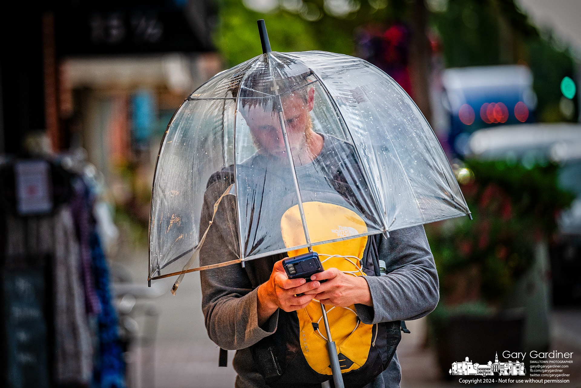 Under the safety of his transparent umbrella, a man shields his phone from an afternoon thunderstorm in Uptown Westerville that brought a substantial amount of rain to the city in several months. My Final Photo for September 6, 2024.