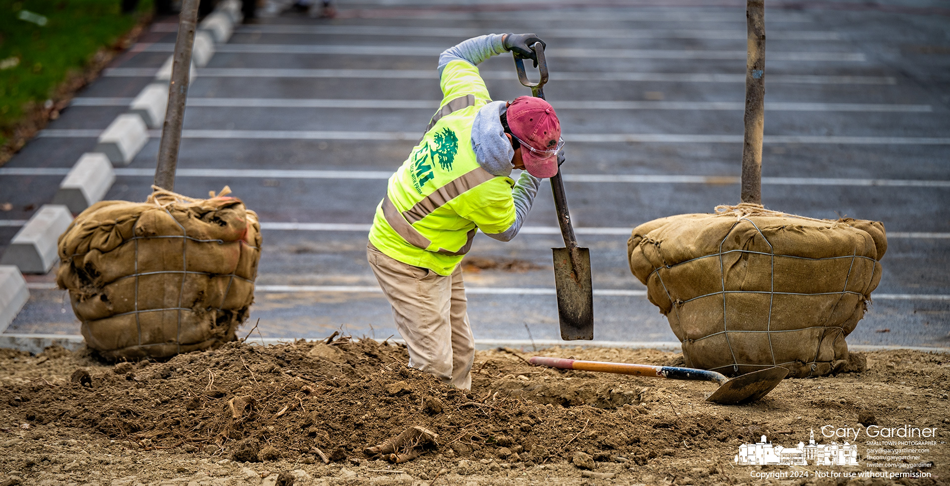 A landscaper digs a hole for a tree in an island in the resurfaced parking ,lot for Otterbeiin's The Point on Collegeview. My Final Photo for October 14, 2024.