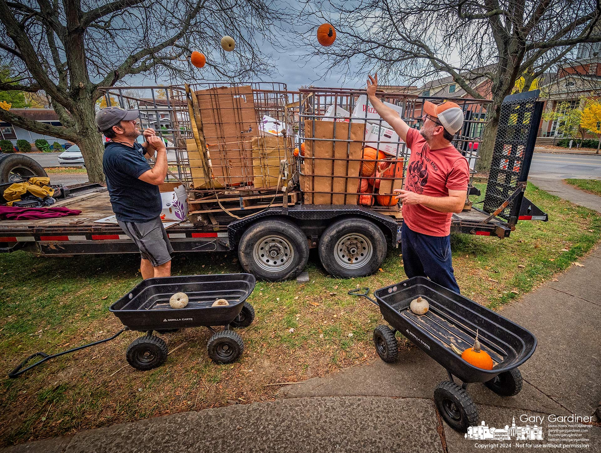 Pete Carmona, left, and Chris Smiley toss pumpkin remainders from the Scout Troop 84 Pumpkin Patch at the Masonic Hall into shipping cages where they will end up on a pig farm as fodder for a porcine dinner. My Final Photo for October 31, 2024.