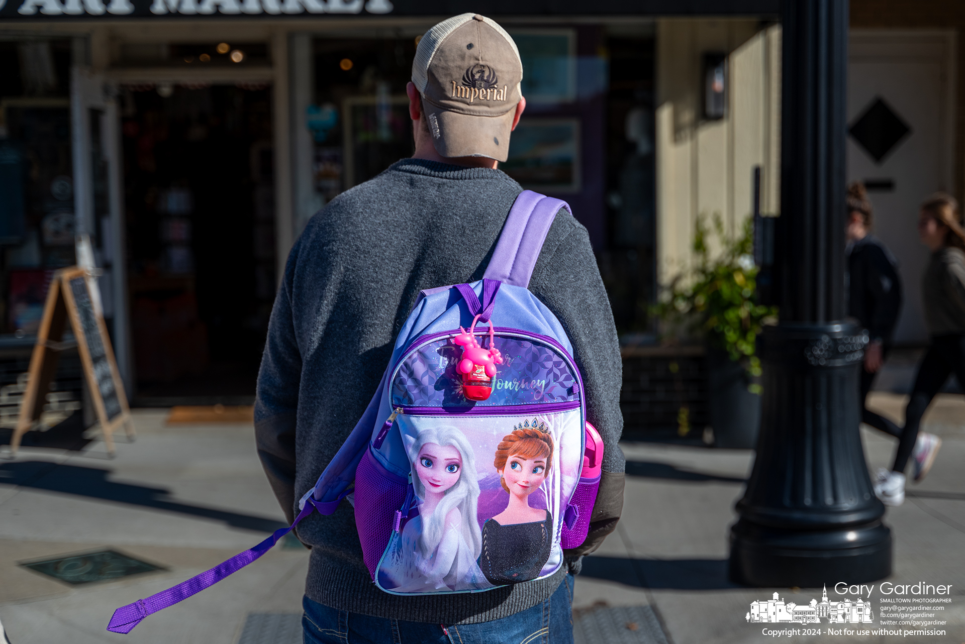 A father matching the meme "Tell me you're a girl dad without telling me you're a girl dad" walks across State Street on his way to Cardinal Pizza with his family. My Final Photo for November 8, 2024.