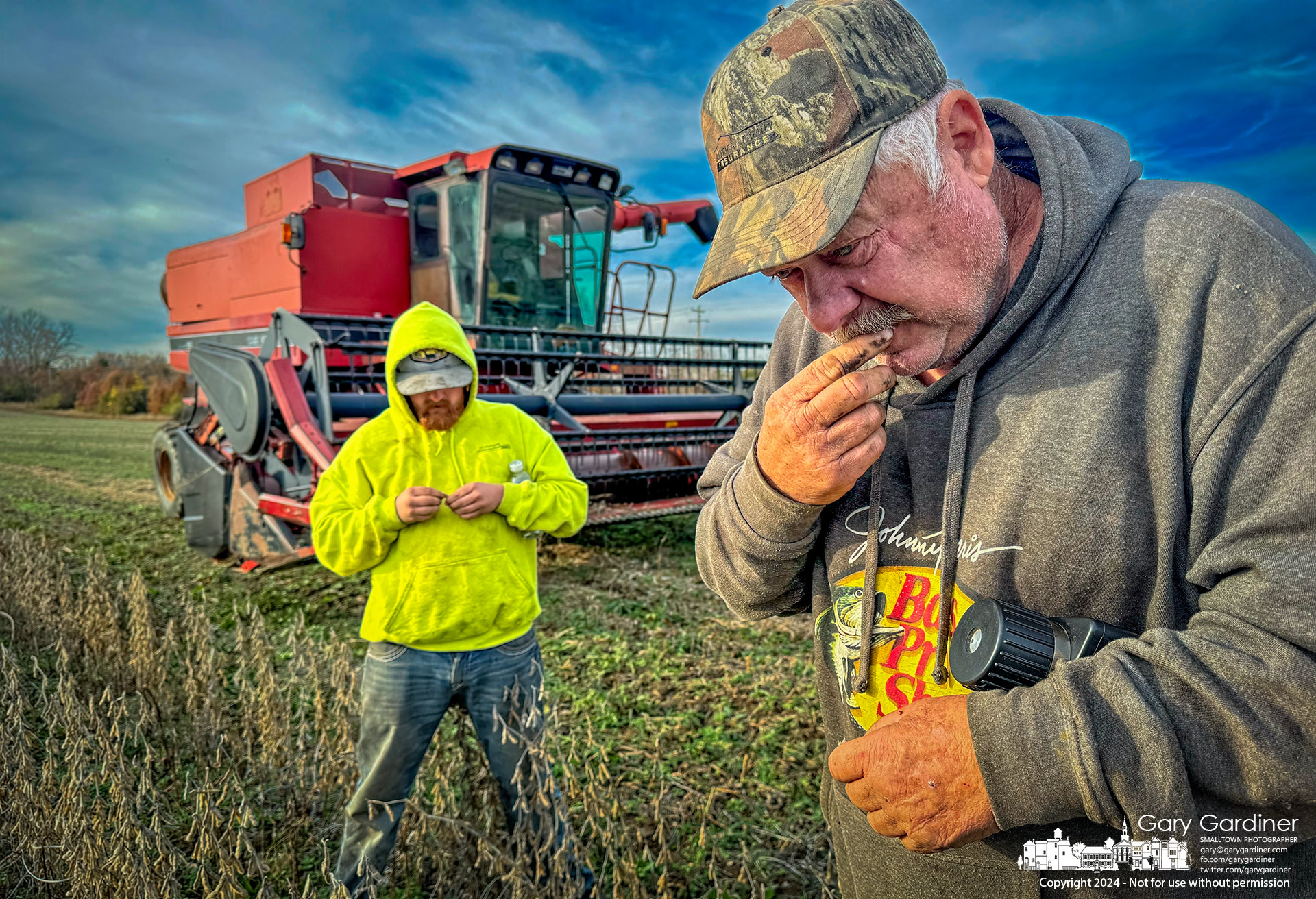 Farmer Kevin Scott, holding a moisture tester under his arm, uses the old-fashioned method of biting into a bean pod to test its moisture content as he tries to decide to continue harvesting beans on the Braun Farm property. My Final Photo for November 17, 2024.