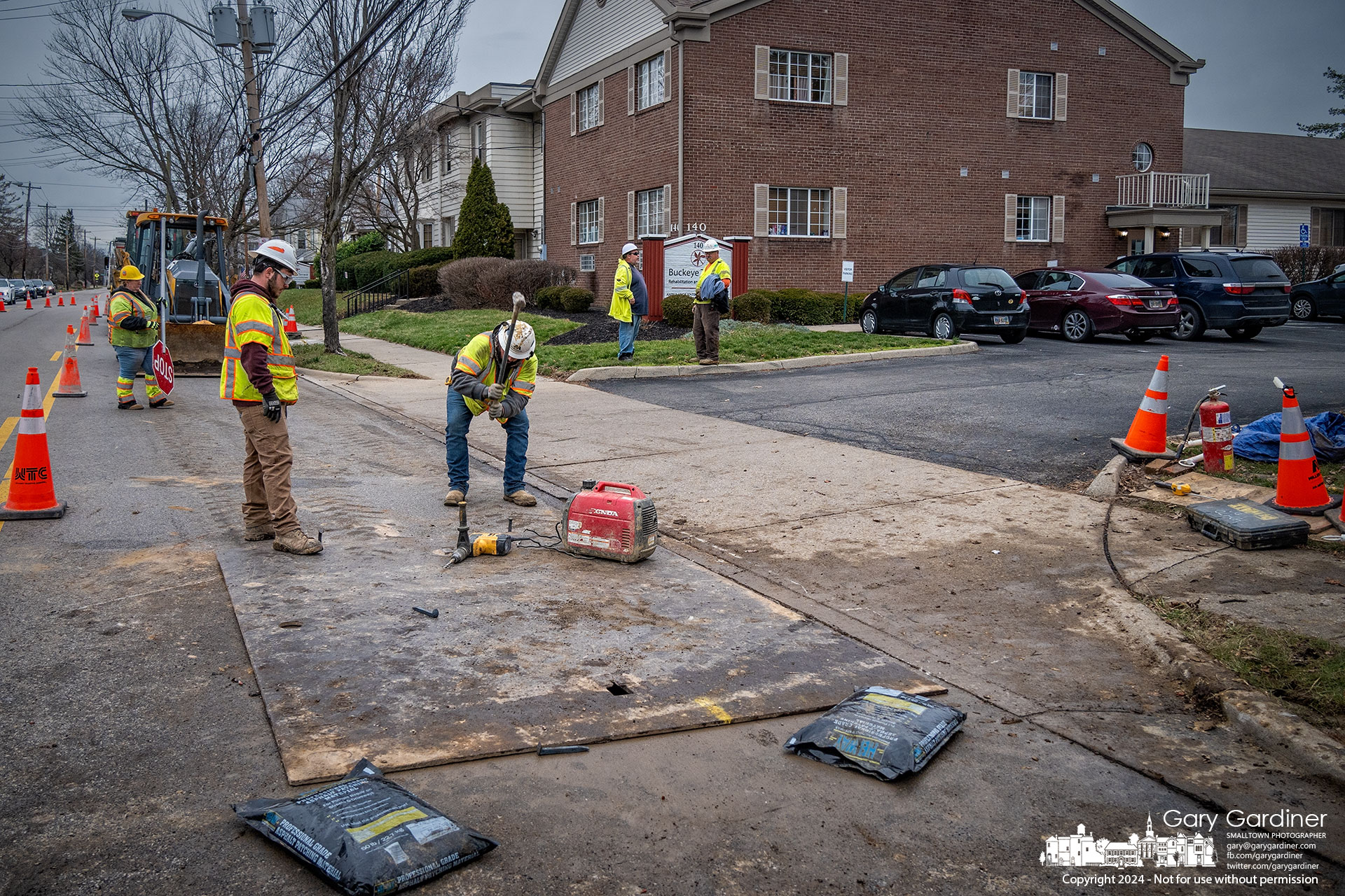 A Columbia Gas work crew attaches a steel plate covering the hole that contained an old gas pipeline leading to a house demolished about twenty years ago. Originally capped at the house, the line needed to be capped in the street at the main pipeline. My Final Photo for December 27, 2024.