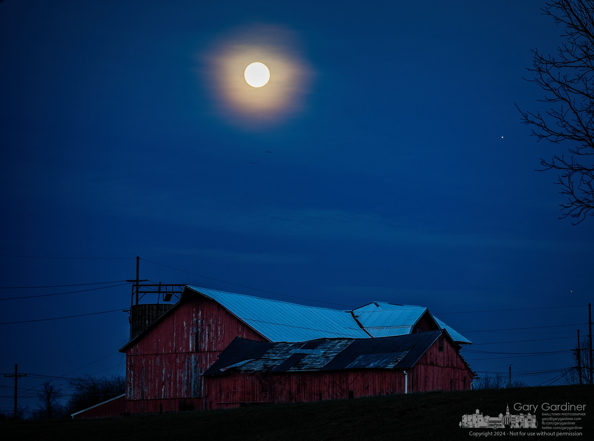 The full moon and Jupiter break through an opening in a cloud layer, illuminating the sky beyond the Yarnell Farm barns. My Final Photo for December 14, 2024.