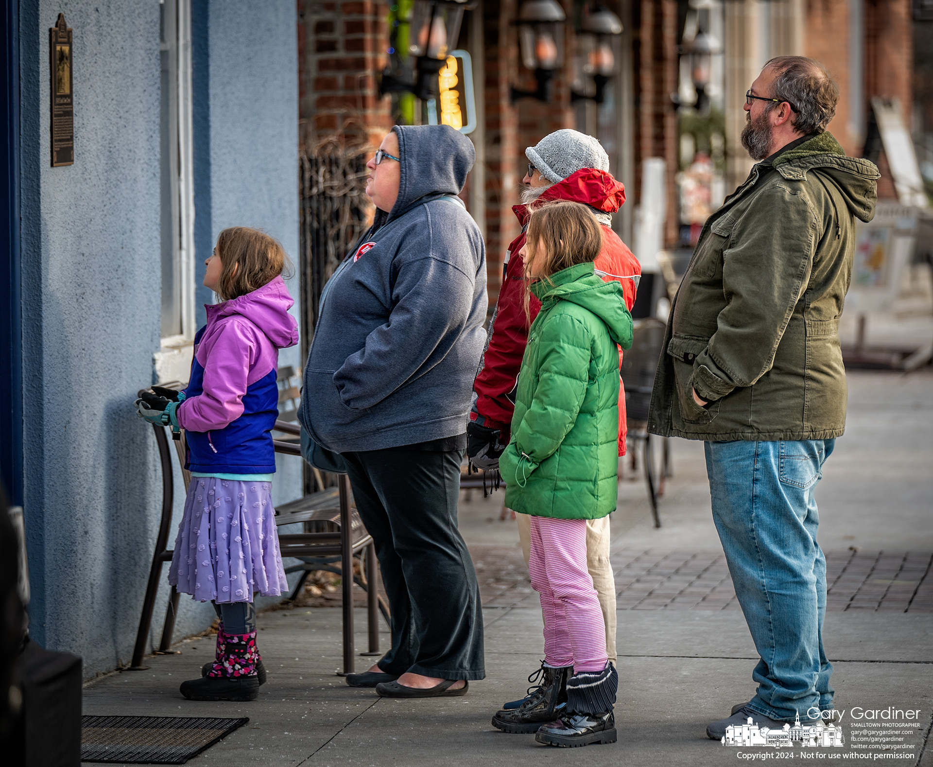 A family stands together reading the historical marker at Westerville Florist as they make their way through Uptown Sunday, reading the plaques and taking in the ice sculptures. My Final Photo for December 22, 2024.