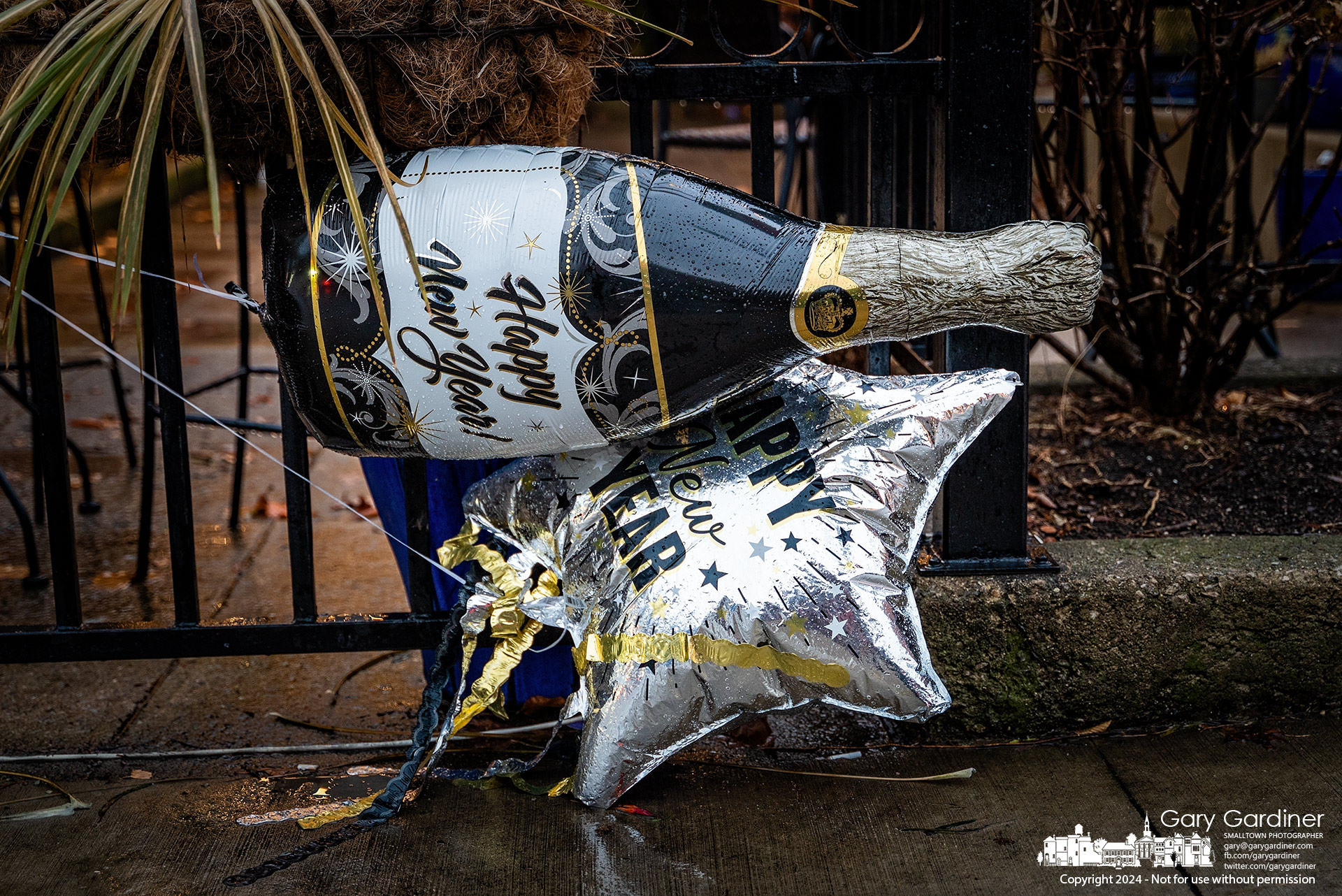 With their helium almost deflated, balloons celebrating the new year float close to the ground and blow in the wind across the sidewalk in Uptown Westerville. My Final Photo for December 31, 2024. 