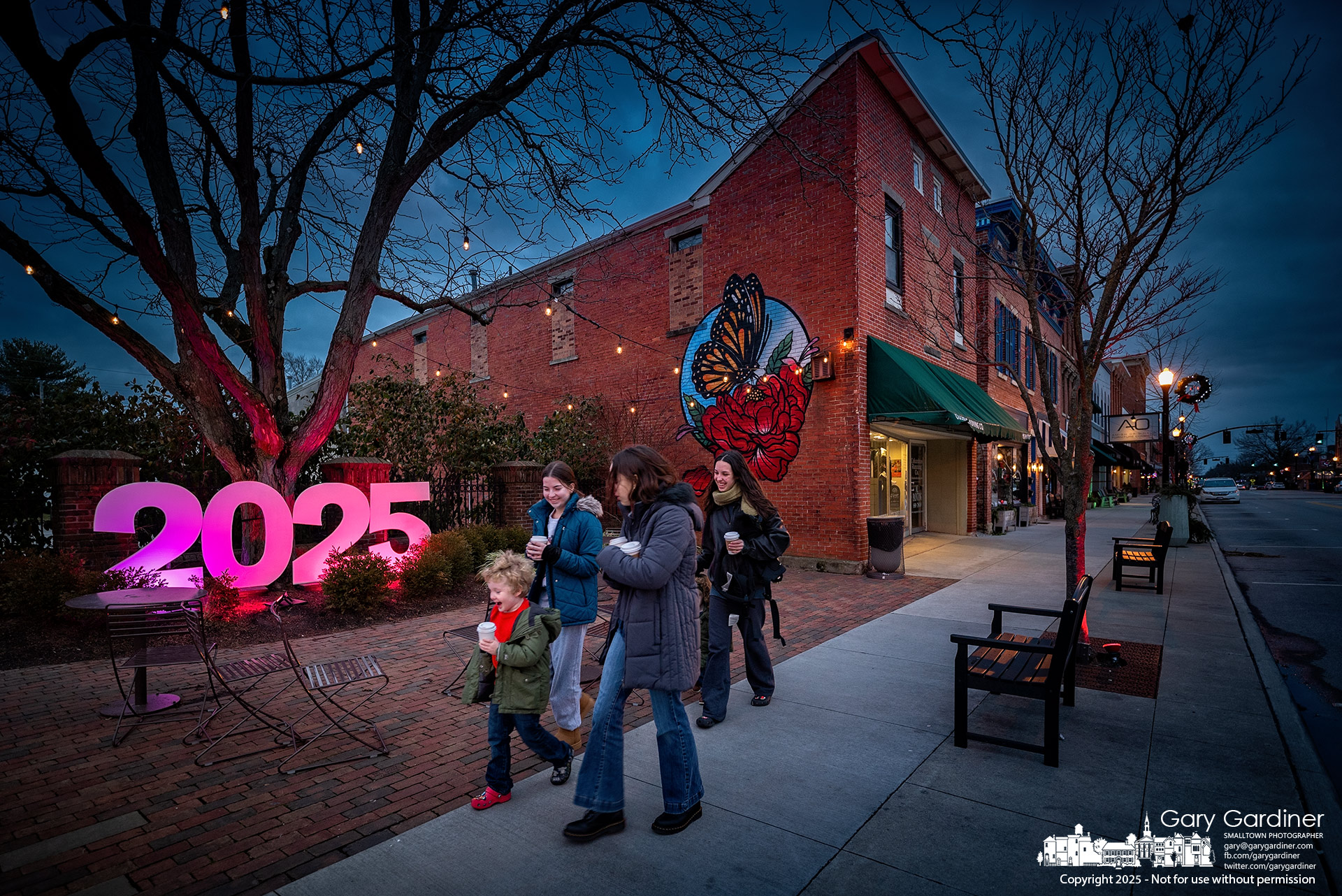 A family walks in the early evening on New Year's Day past the 2025 sign displayed for photos and selfies in Rotary Park at Home and State Streets in Uptown Westerville. My Final Photo for January 1, 2024.