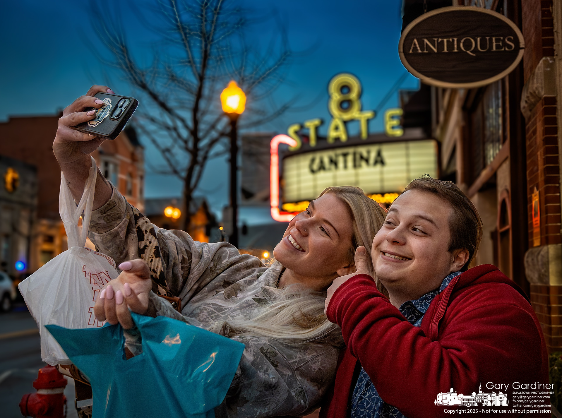 Caroline Johnson and Spencer Echemann pose for selfies in front of the window at Westerville Antiques after shopping in Uptown Westerville and heading to the grocery store to get cinnamon roll ingredients for Sunday Morning breakfast. My Final Photo for January 18, 2025.