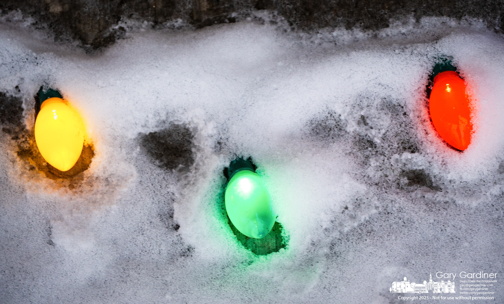 A set of Christmas lights reveal themselves, having melted their warm glow through the snow that covered them on the edge of a sidewalk in Uptown Westerville. My Final Photo for January 7, 2025.