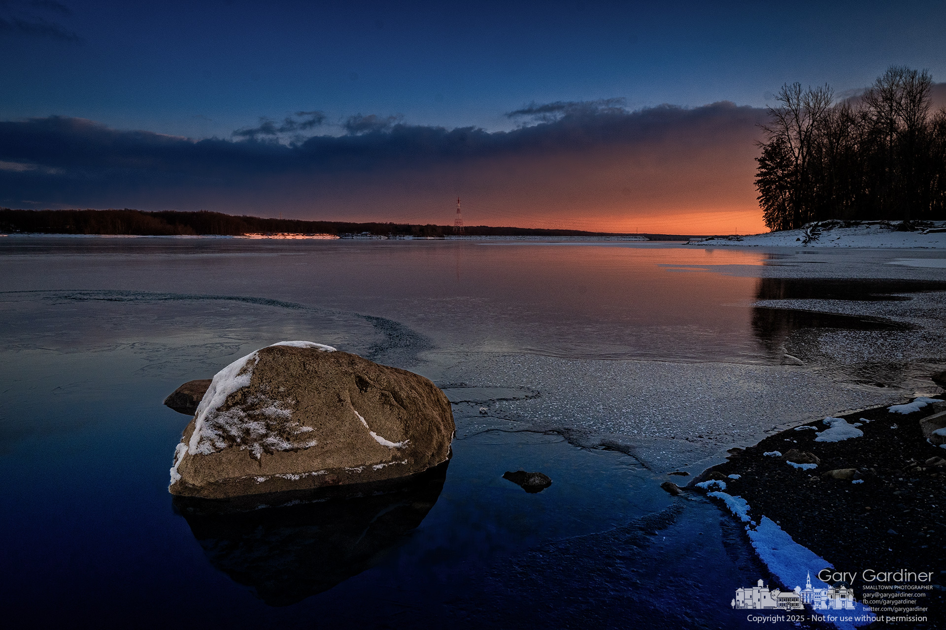 The late afternoon glow lights the horizon at Hoover Reservoir, where a rock exposed by the lake's low waters is slowly encased in a layer of ice as the lake freezes in the low temperature. My Final Photo for January 9, 2025.