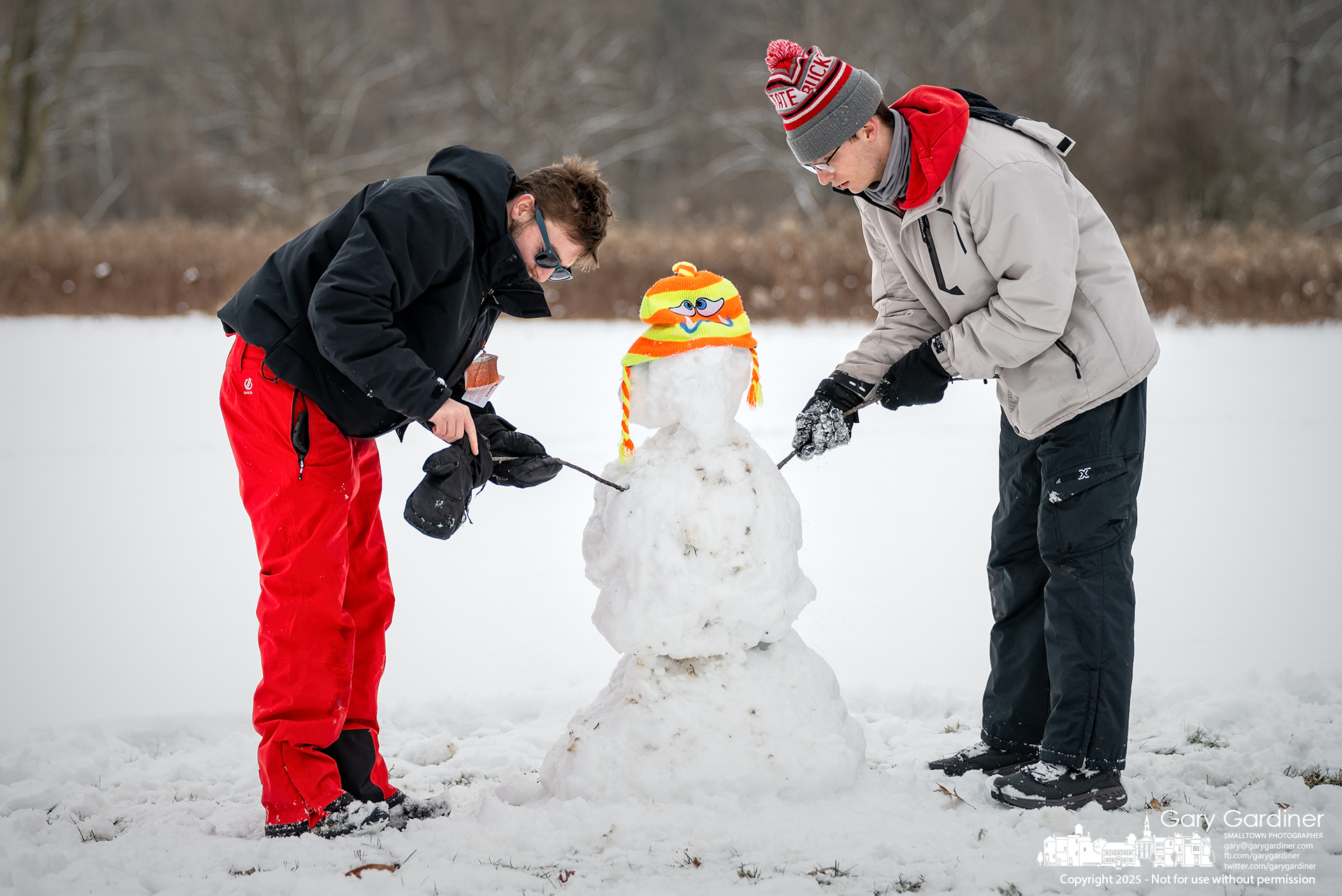 Shawn Korkorean, left, and Aidan Valentine shove sticks into a snowman and create arms for the snow memory at Sharon Woods Park of Korkorean's outdoorsman father, who recently died. My Final Photo for January 11, 2025.