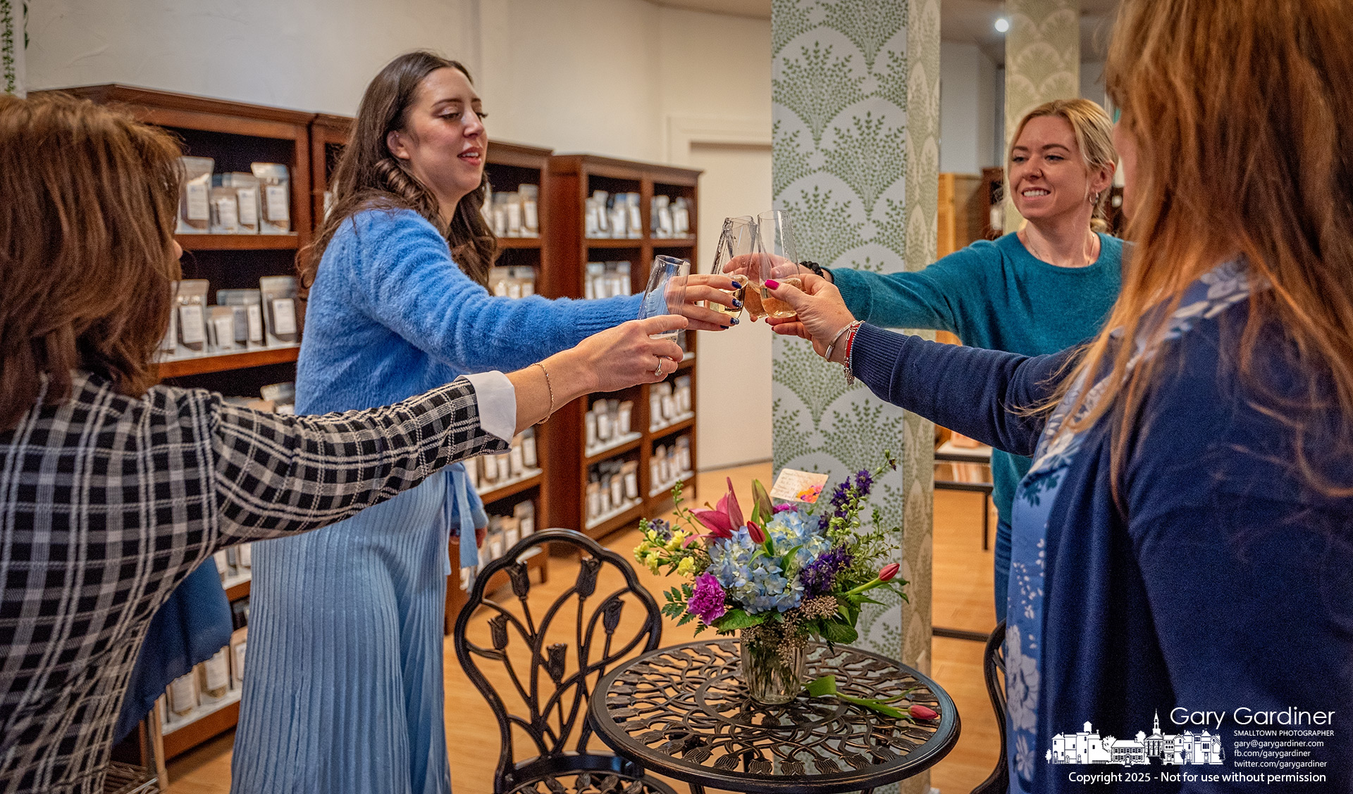 Blue Turtle Tea and Spice owner Alex Maddox, second from left, celebrates with friends and family a champagne toast for the grand reopening of her store on East College Saturday morning. My Final Photo for February 8, 2025.