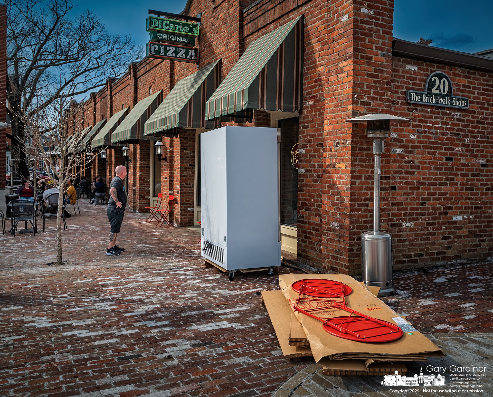 Before moving the new beer cooler into DeCarlo's Pizza, a worker visually inspects the door dimensions and determines it will fit but requires help due to its bulk. My Final Photo for March 15, 2025.