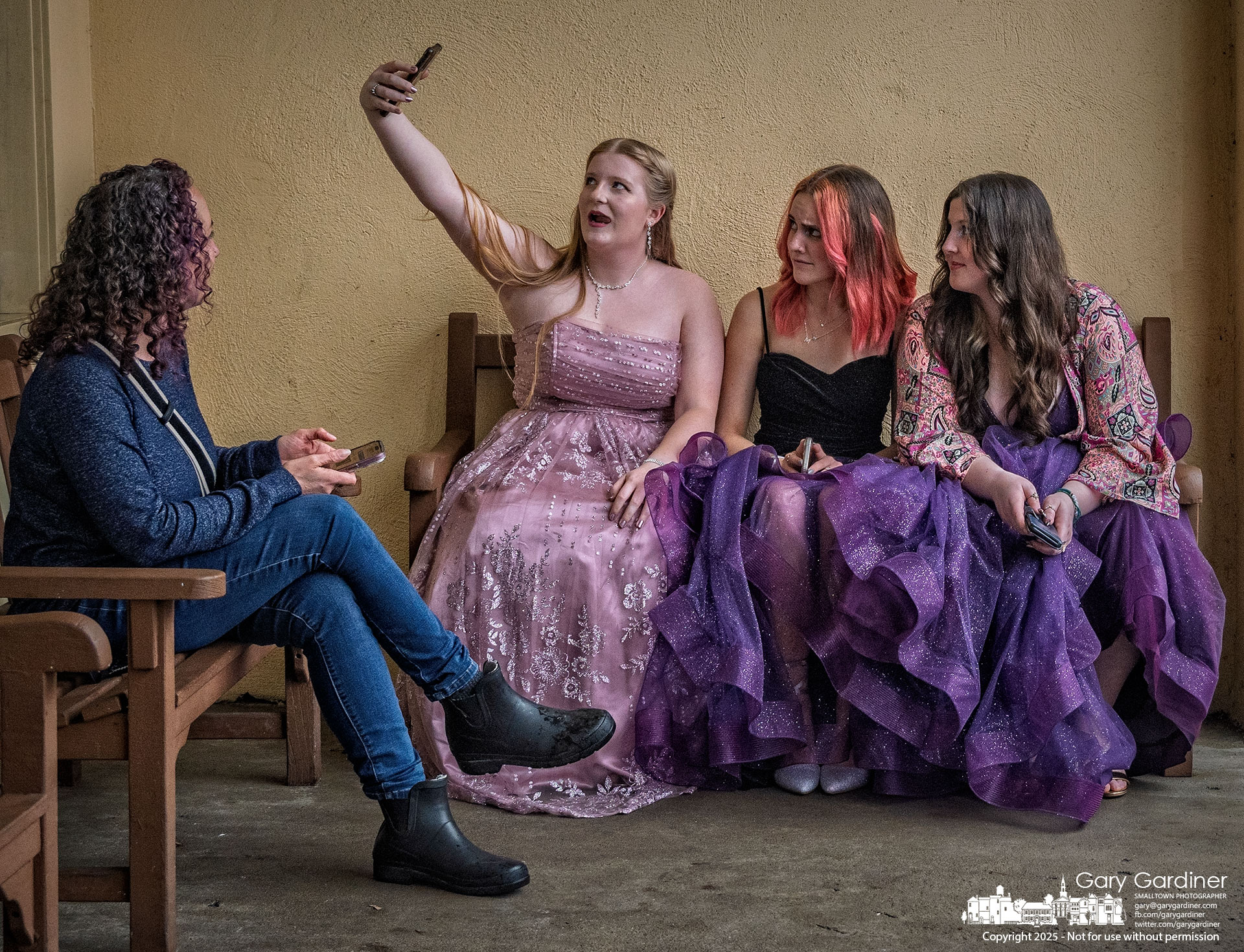 After posing for more formal photos in their prom gowns in Uptown's most picturesque location, three girls finish the evening with a selfie on the bench in front of Graeter's. My Final Photo for April 5, 2025.
