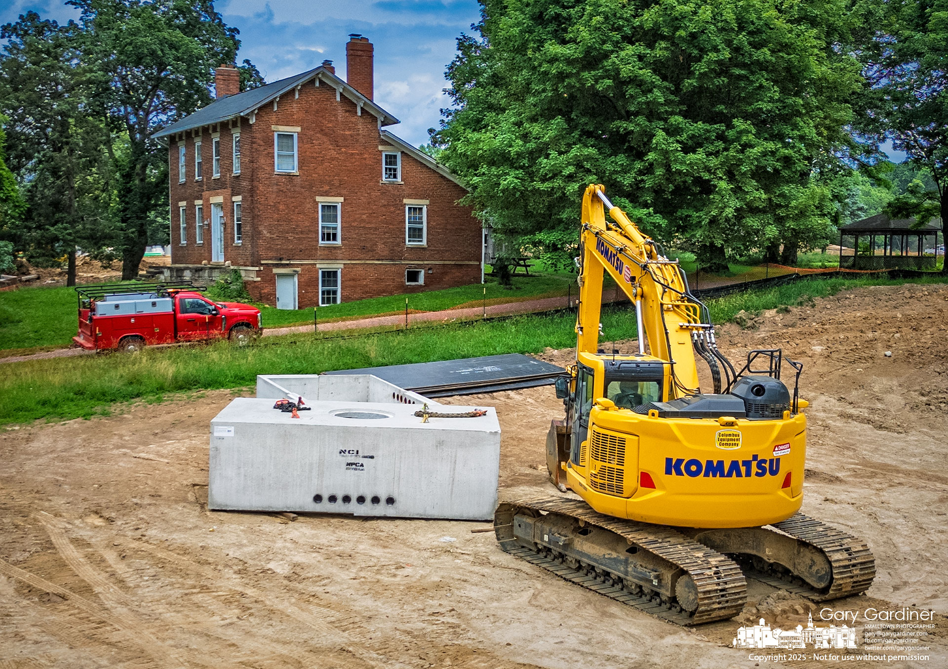 A pre-formed concrete utility vault sits beside an excavator parked on a former sloping hill that once led to the Sharp House. The city is now preparing the site with underground utilities to become a road connecting Arica Road to the East of Africa development project. My Final Photo for June 16, 2025.