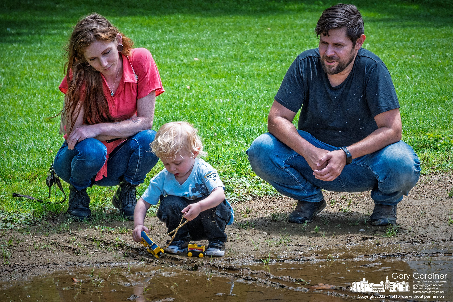 After getting the nod from his parents, a three-year-old eagerly plays with his toy trucks in the muddy infield at the Alum Creek Park baseball field. My Final Photo for June 19, 2025.