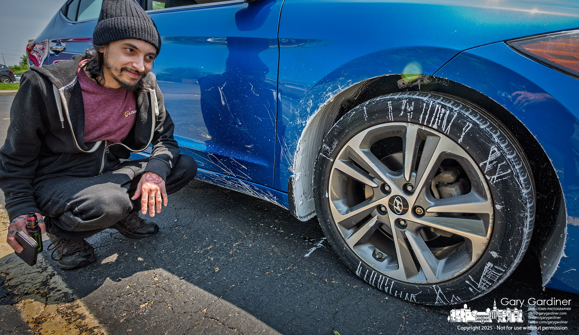 A driver inspects his car after 10 five-gallon buckets of white roofing sealant fell from a truck in front of him at State Street and Maxtown Road, forcing the closure of the intersection into the evening for cleanup. My Final Photo for June 2, 2025.