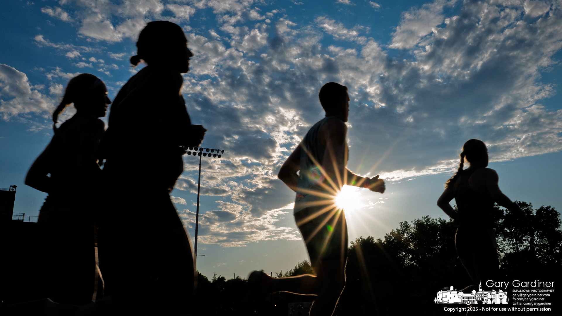 Silhouetted against the setting sun, runners complete one of four laps around the Otterbein track during a heat of the Sunset Mile, a series of paced one-mile races held Friday. My Final Photo for June 20, 2025.