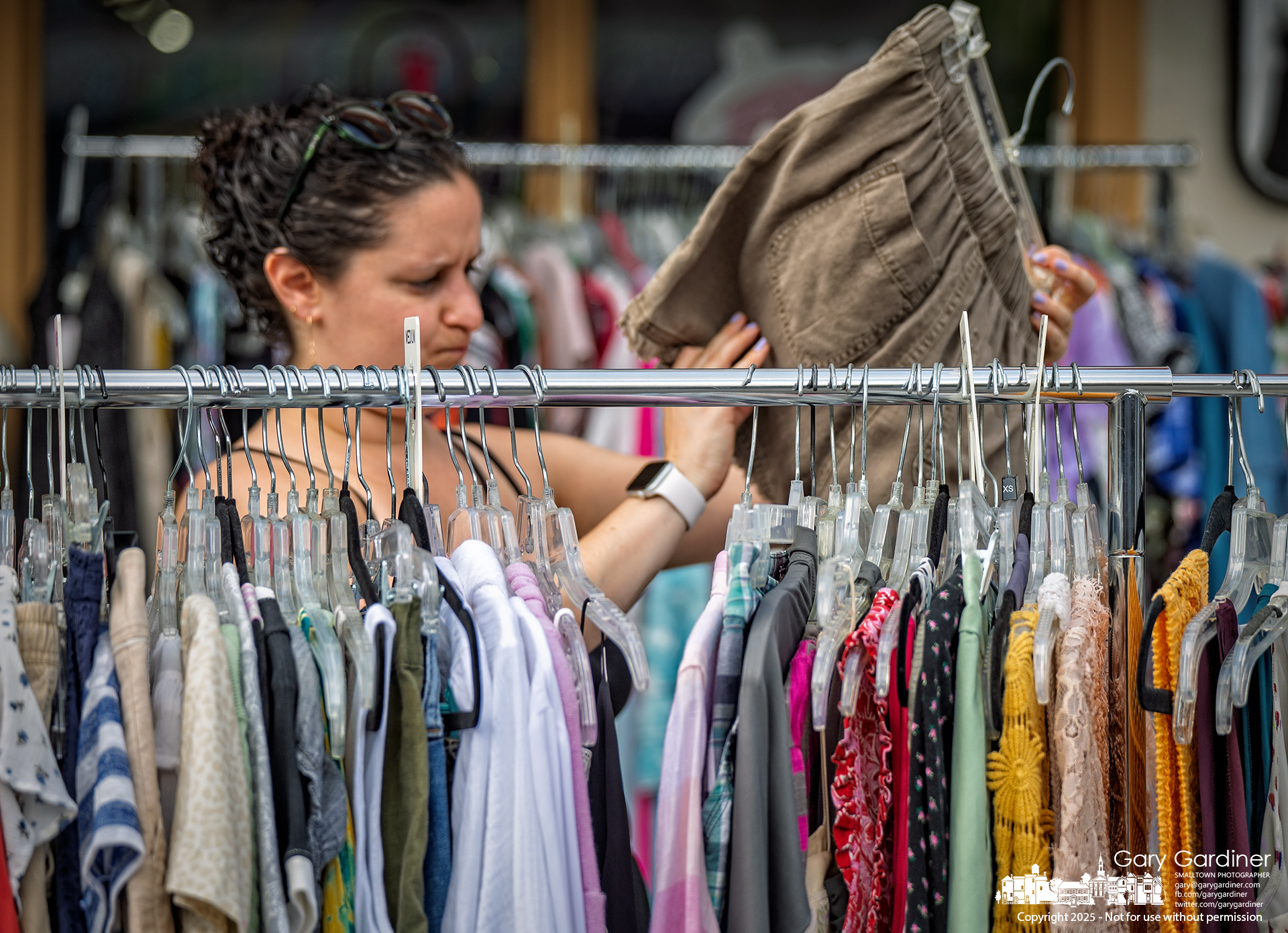 A shopper inspects shorts pulled from the markdown racks in front of the Deja Vu shop in Uptown Westerville. My Final Photo for July 26, 2025.