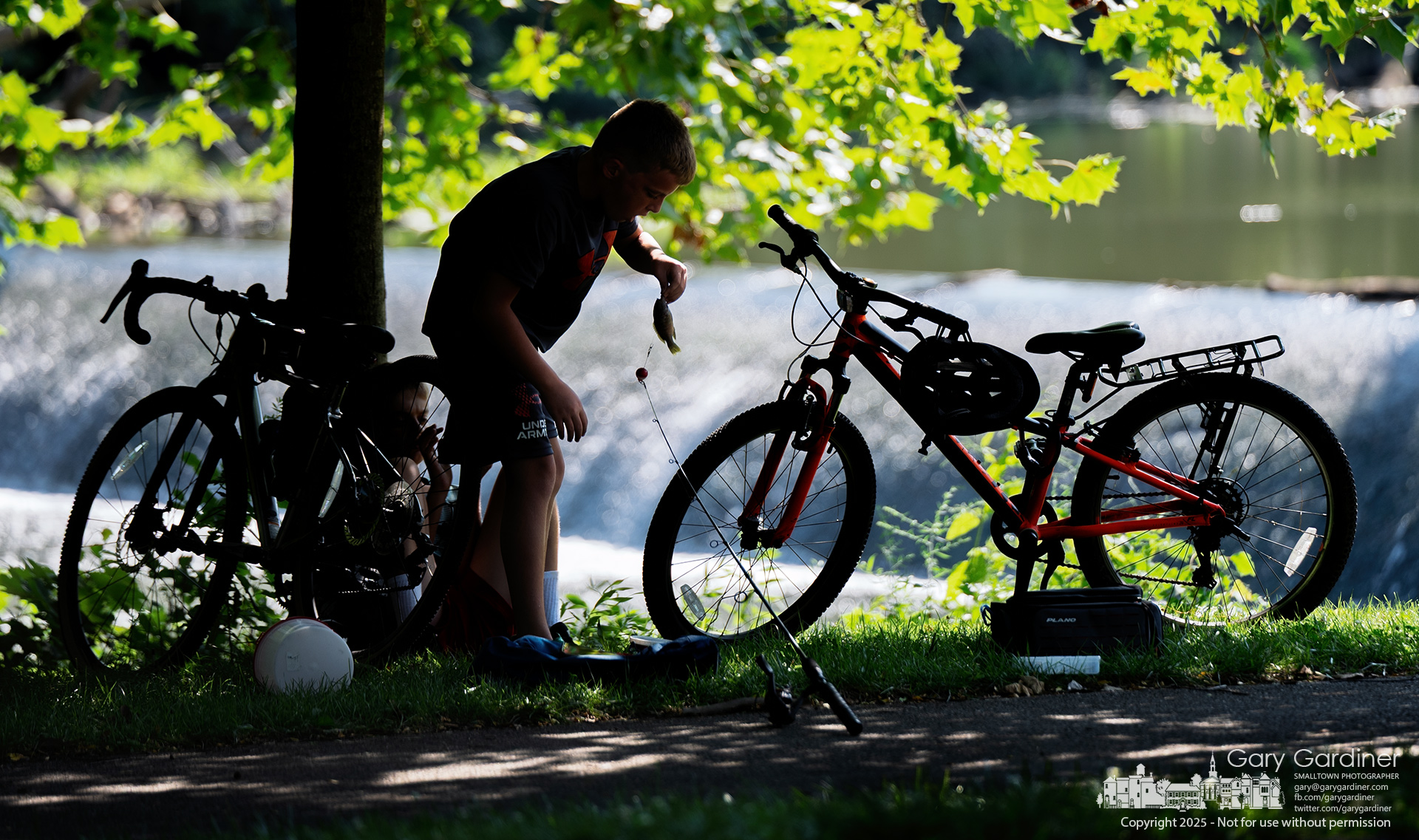 In the shade of a creekside tree, a young angler works to unhook a small fish he just caught below the Alum Creek Dam. My Final Photo for August 1, 2025.