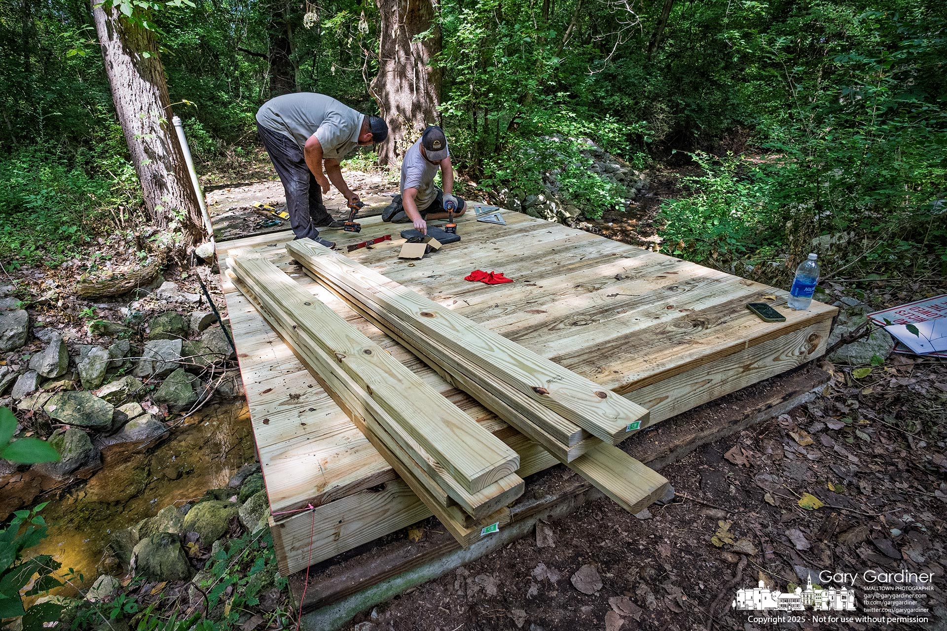A landscaping crew rebuilds a bridge over a small creek on a path connecting two of Otterbein’s sports fields west of North West Street. My Final Photo for August 14, 2025.