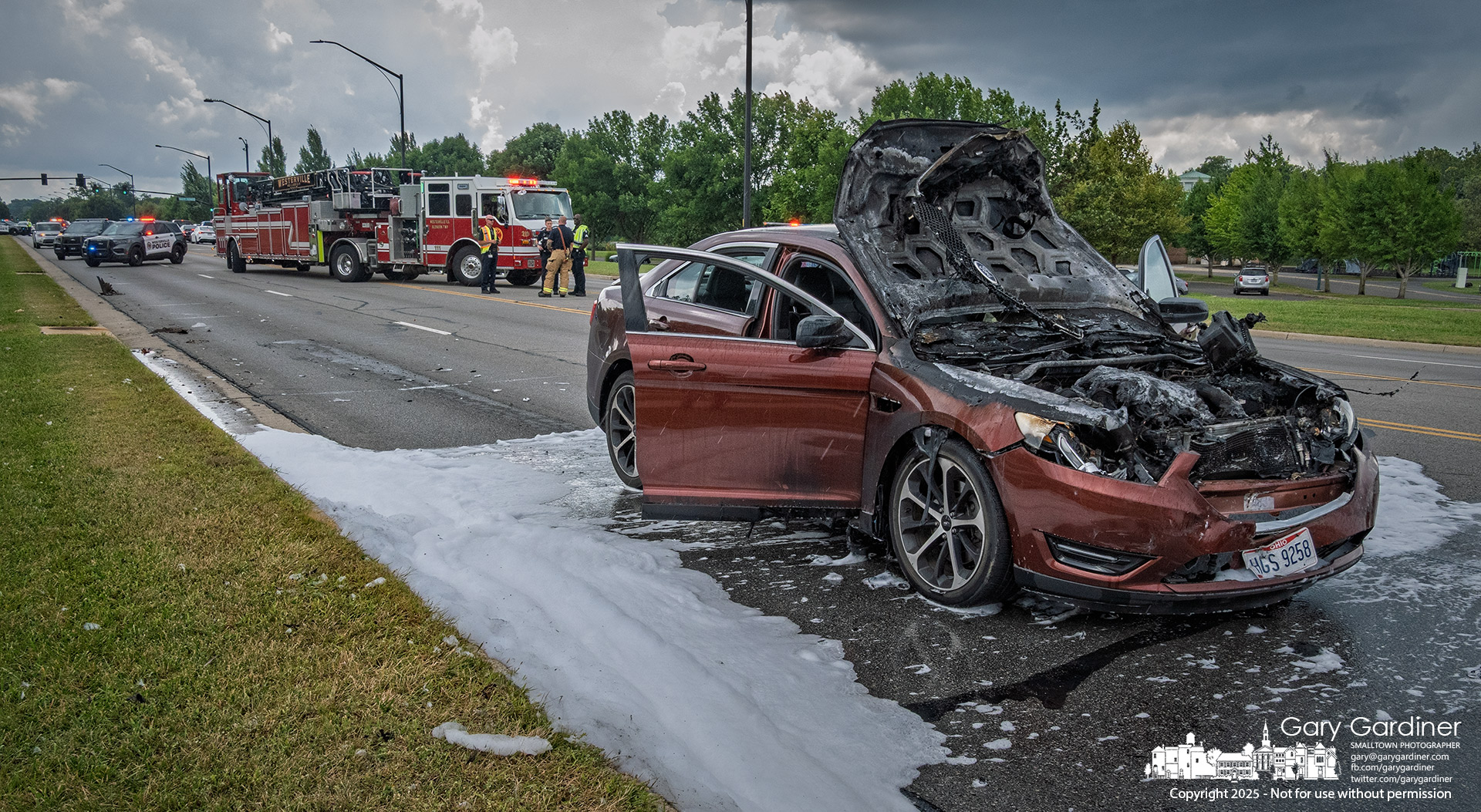 Firefighting foam used to extinguish a car blaze on Cleveland Avenue flows into the gutter as police and firefighters wait for a wrecker to remove the damaged vehicle. My Final Photo for August 13, 2025.
