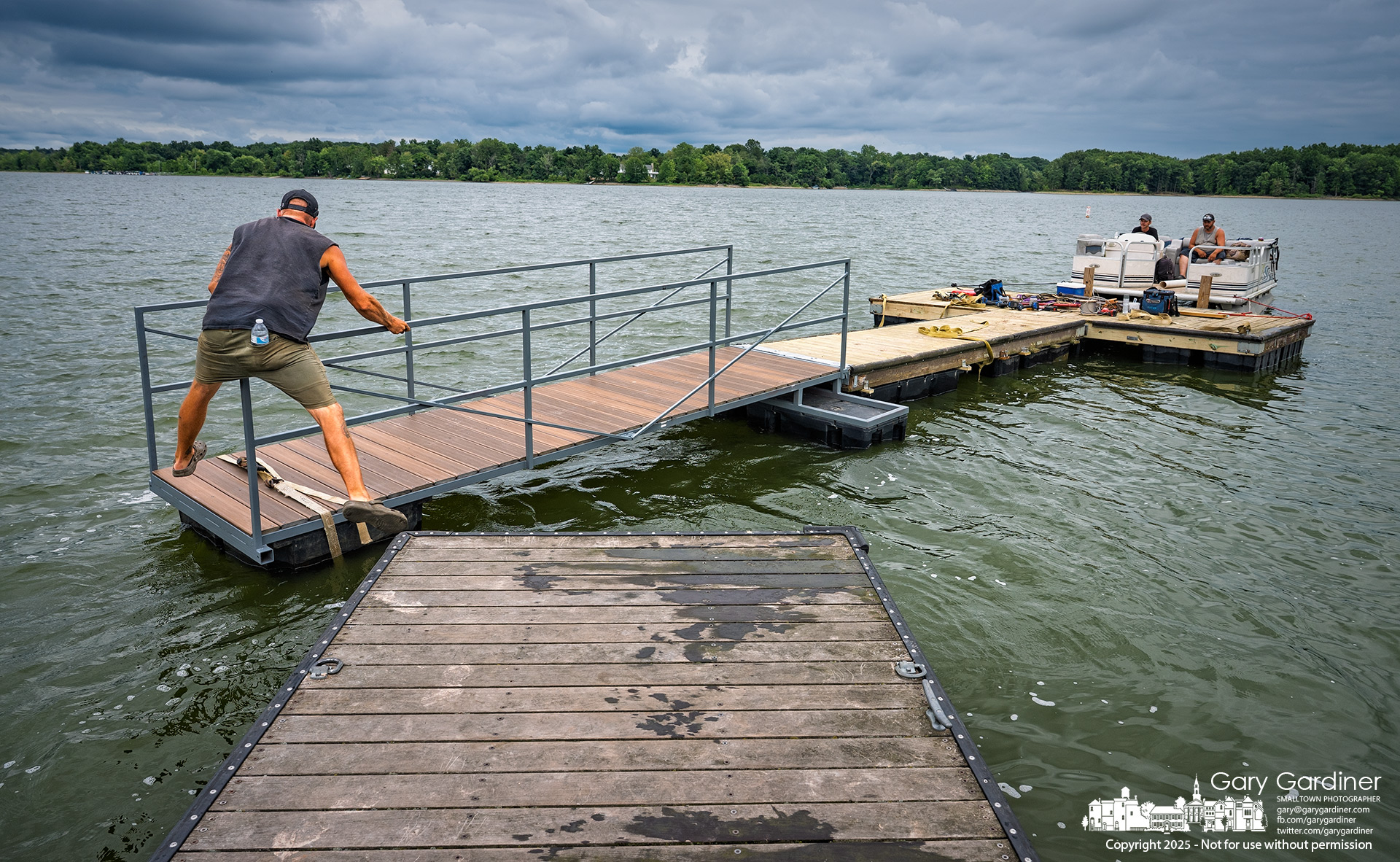A dock builder jumps from an anchored dock at Red Bank Marina to a moving one as a crew moves a rebuilt old dock and new ramp across Hoover Reservoir to its home shore. My Final Photo for August 20, 2025.