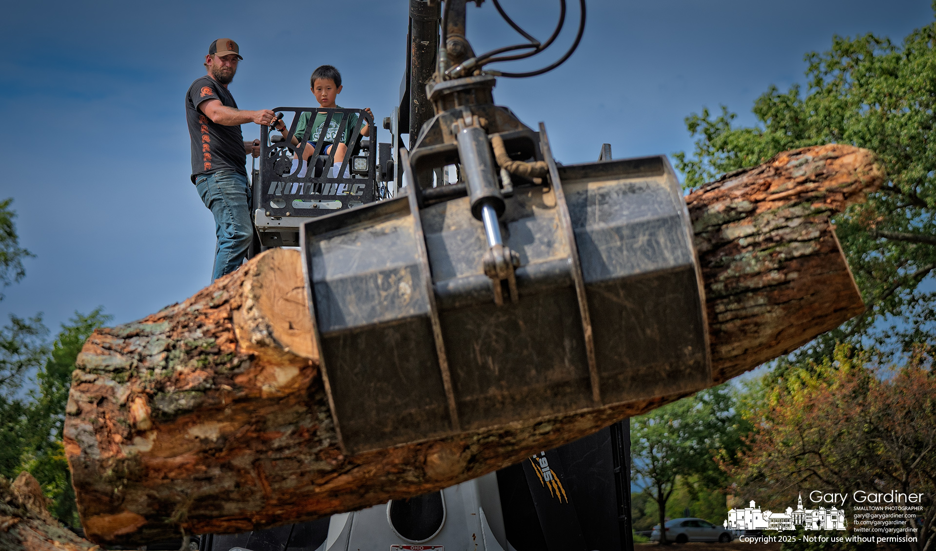 A young boy operates the grappling arm of a tree service truck to lift a section of tree trunk, with guidance from a professional, during Saturday’s Arborfest at Alum Creek Park. My Final Photo for September 20, 2025.