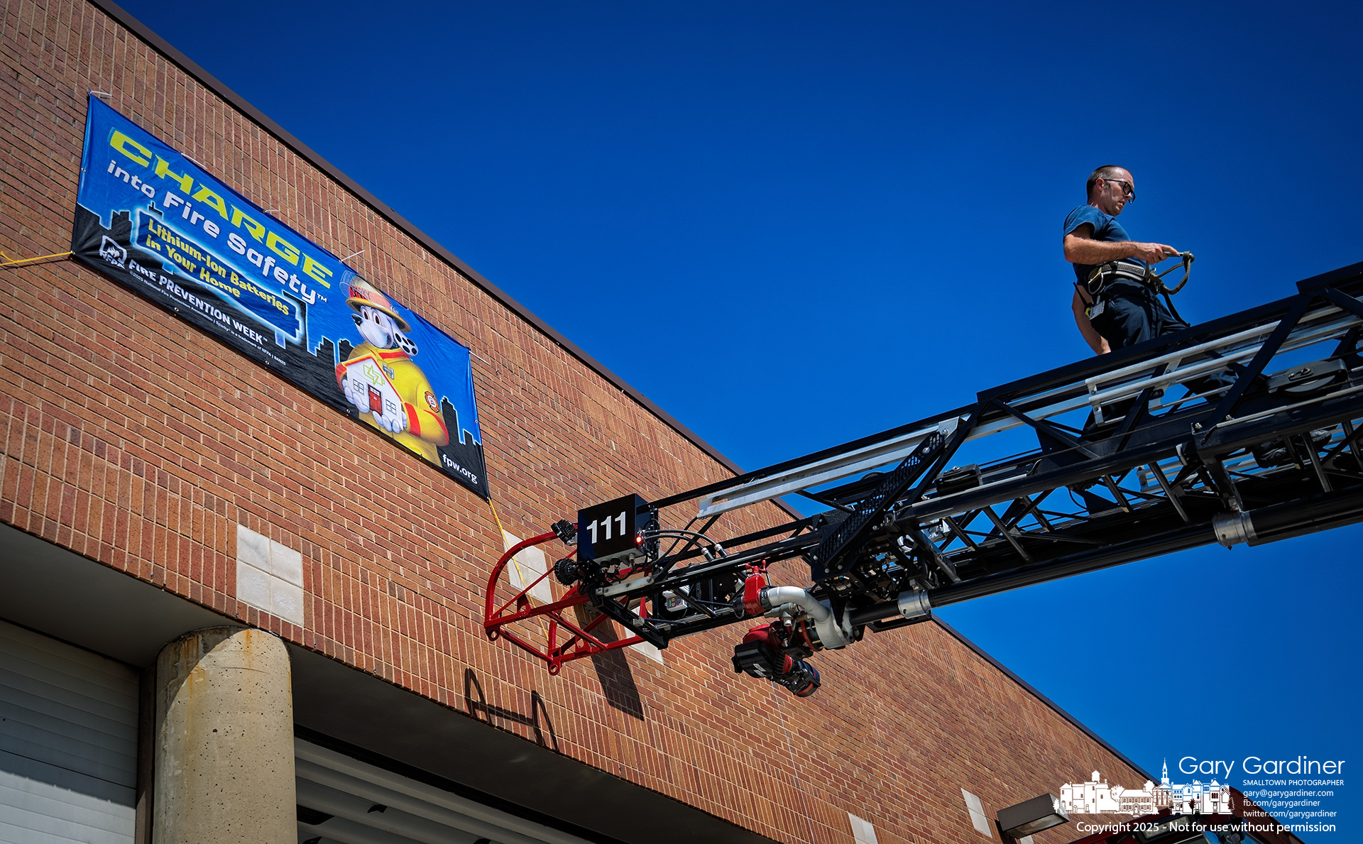 A Westerville firefighter climbs down Ladder 111 after placing a banner on the main fire station for Fire Prevention Week, which includes warnings about rechargeable batteries. My Final Photo for September 1, 2025.