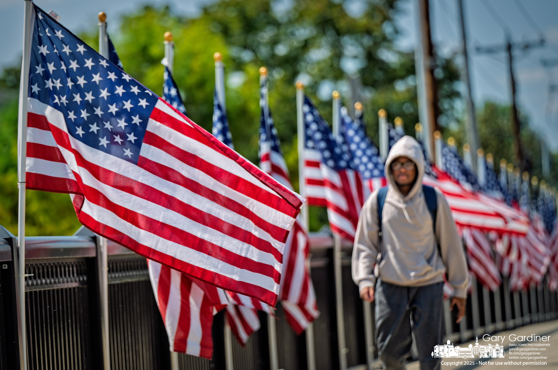 An Otterbein student walks across the Main Street bridge, which was decorated with American flags on Monday as part of this week’s 9/11 remembrance. My Final Photo for September 8, 2025.