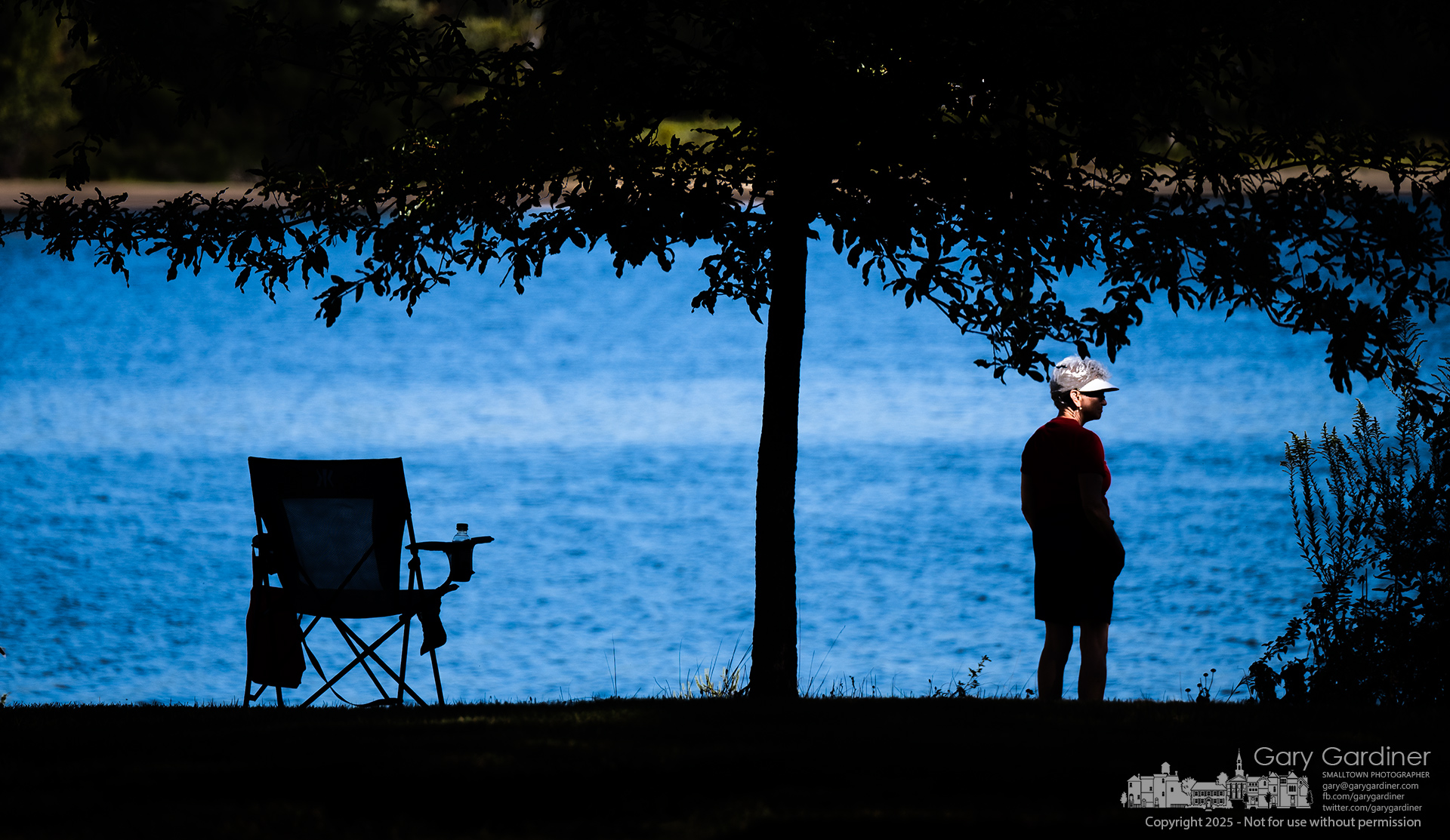 A woman sitting in the shade along the shoreline at Hoover Reservoir steps into a ray of sunlight as she takes a brief walk late Thursday afternoon. My Final Photo for September 11, 2025.