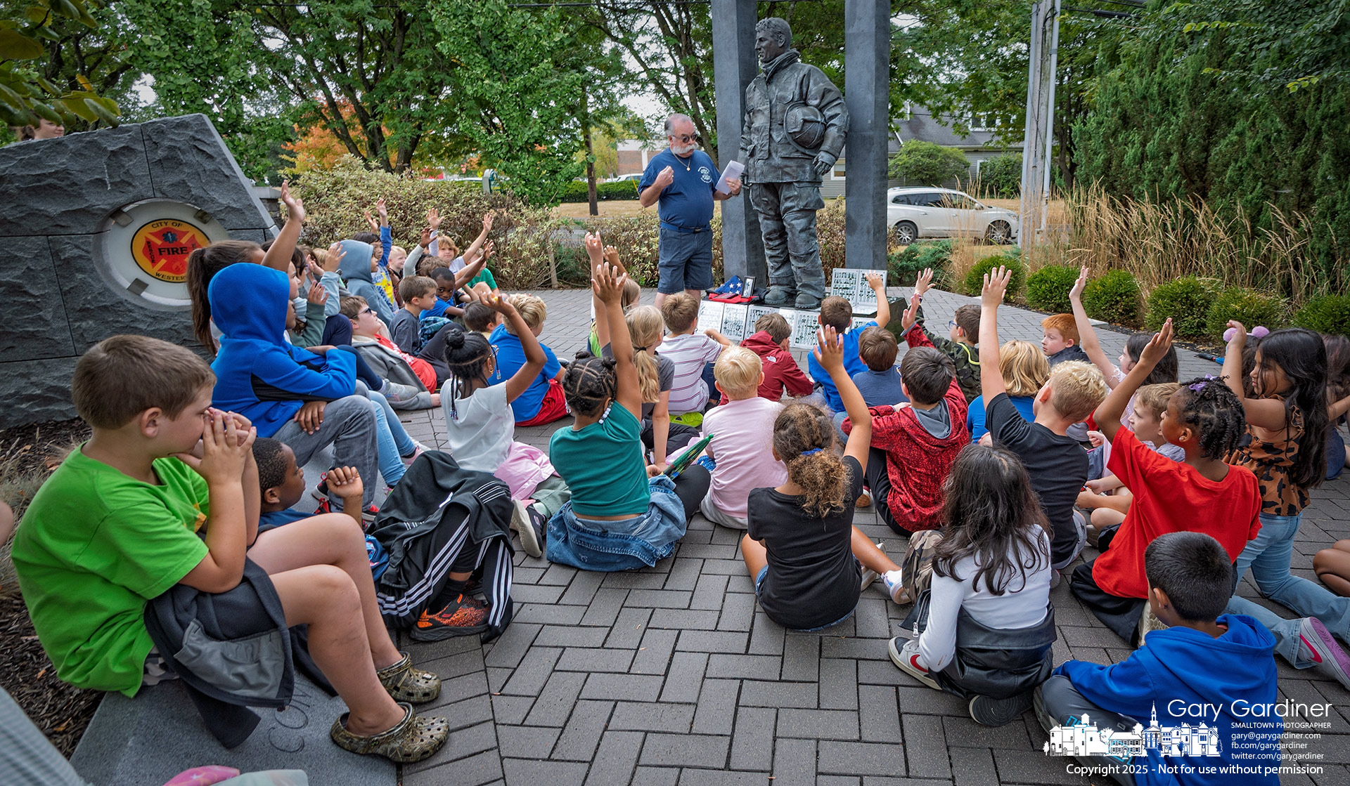 Retired Westerville firefighter Tom Ullom talks to third-graders from Hanby Elementary about “The Crossing” sculpture in First Responders Park during a field trip tied to their 9/11 studies.