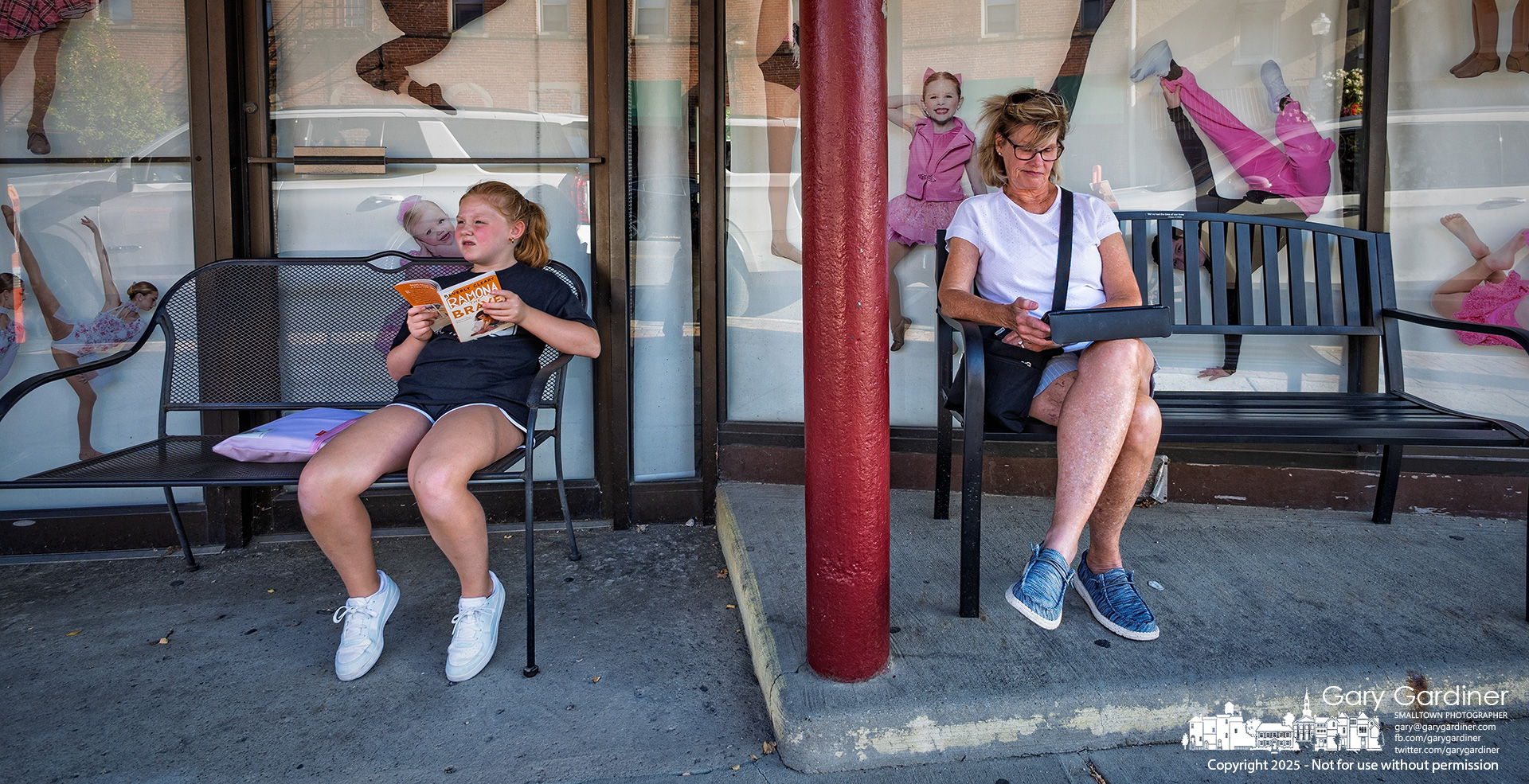 Defying the modern stereotype of readers, a woman reads from a tablet while a young girl looks up from a printed book outside Generations in Uptown Westerville. My Final Photo for September 17, 2025.