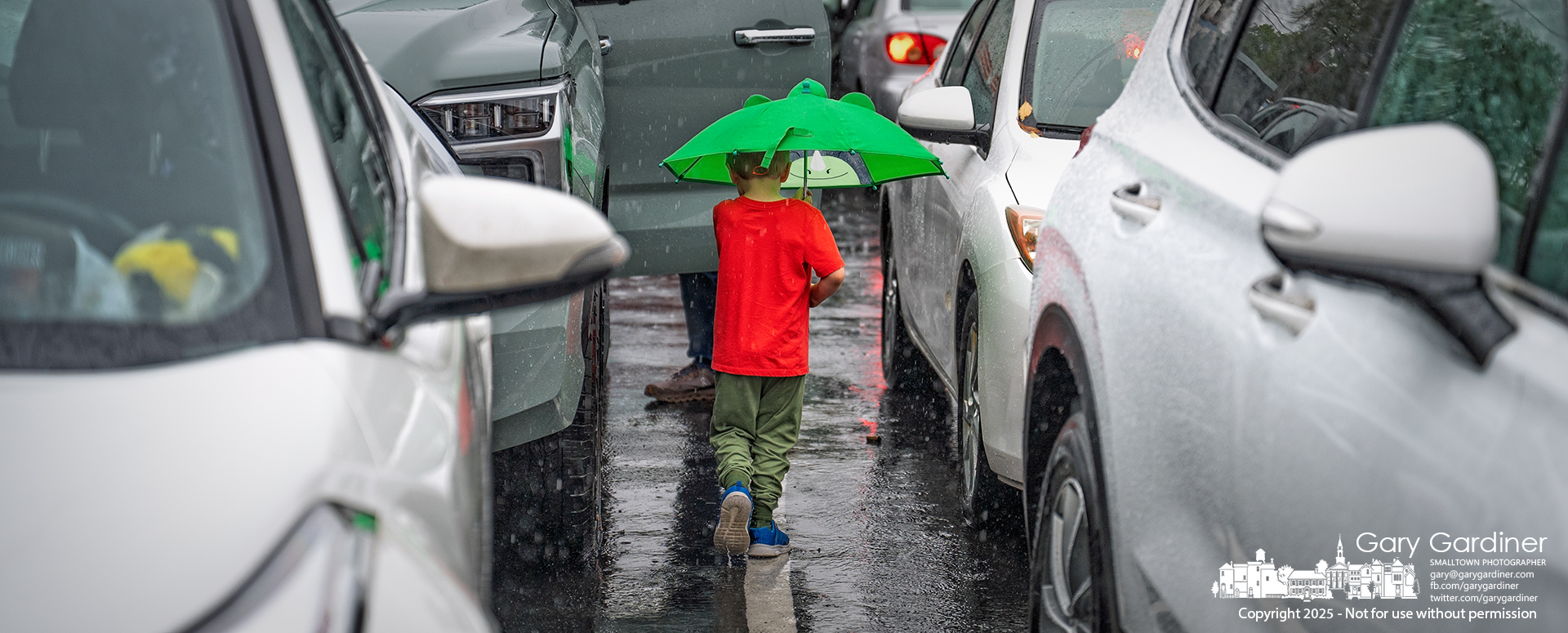 A young boy carrying his favorite frog umbrella follows his father through Uptown rain on Tuesday afternoon, on his way to the car and home. My Final Photo for October 7, 2025.