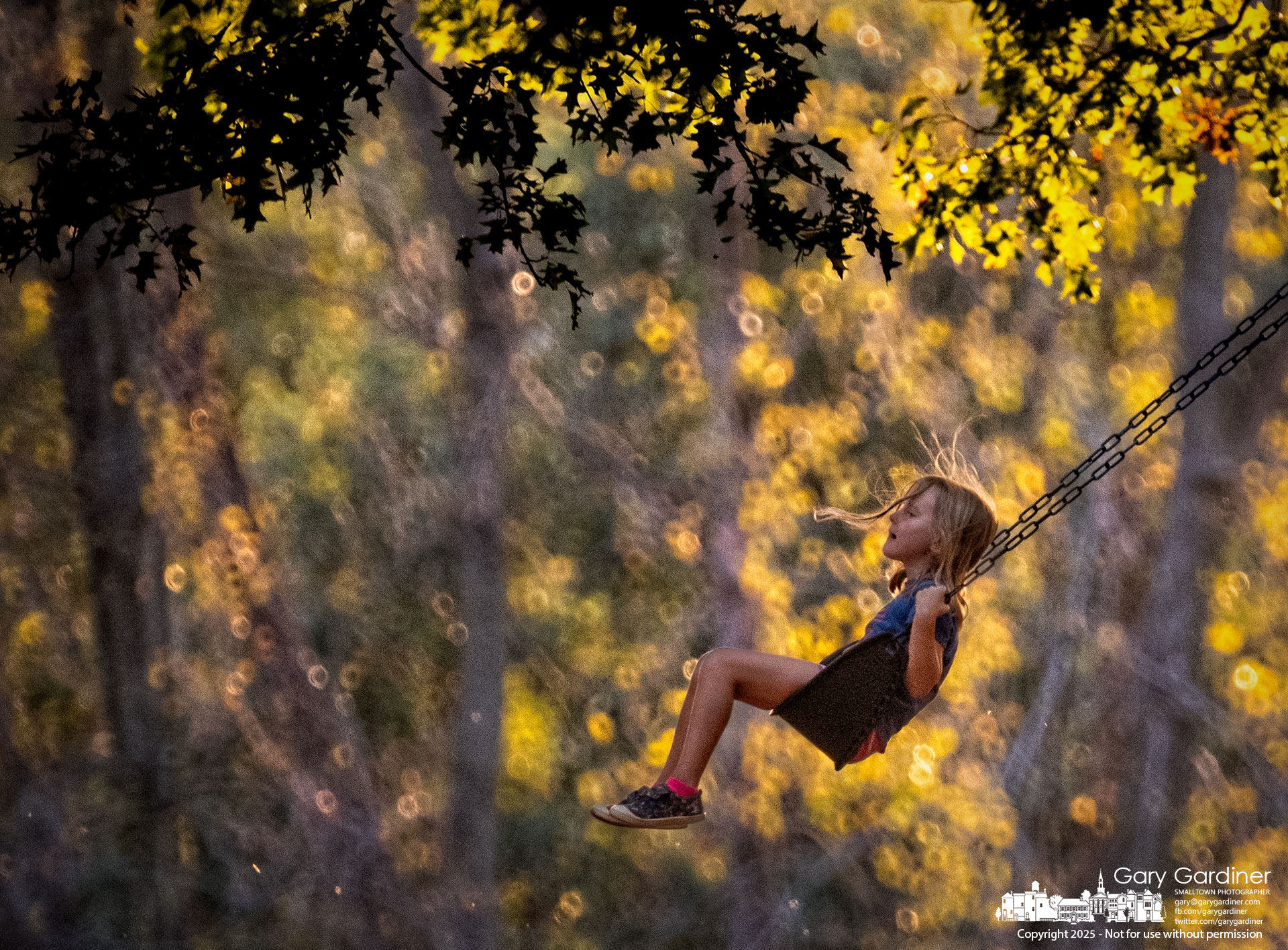 A young girl’s hair flies as she swings back, bathed in the warm colors of sunset, pushed by her mother at Sharon Woods Park. My Final Photo for October 4, 2025.