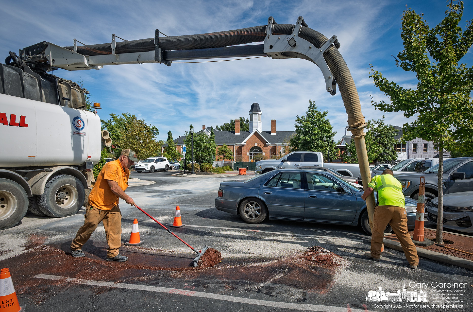 Workers vacuum a drying agent from the City Hall parking lot after a truck's hydraulic system leaked fluid on the pavement. My Final Photo for October 2, 2025.