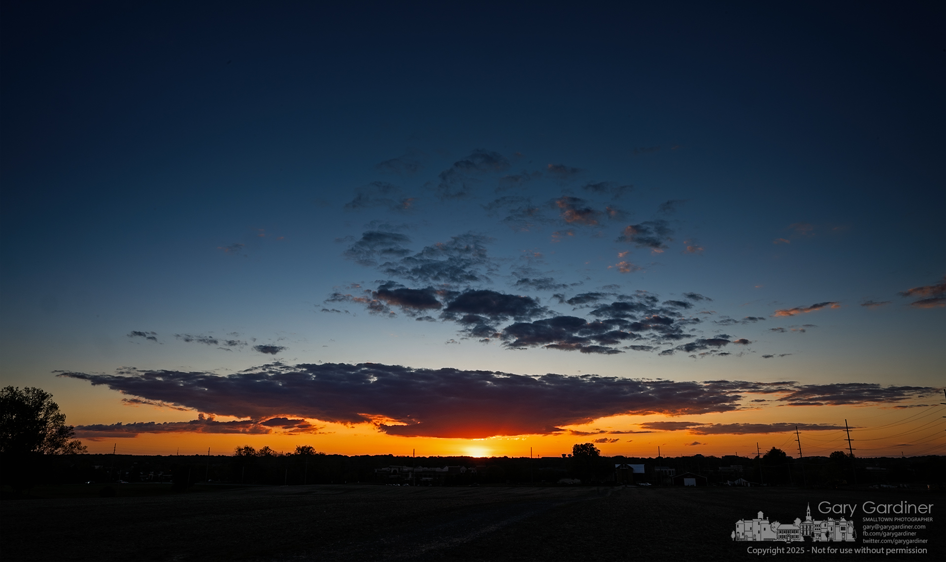The sun sets beyond the treeline at Alum Creek, with outlines of Yarnell Farm structures punctuating the silhouette. My Final Photo for October 12, 2025.