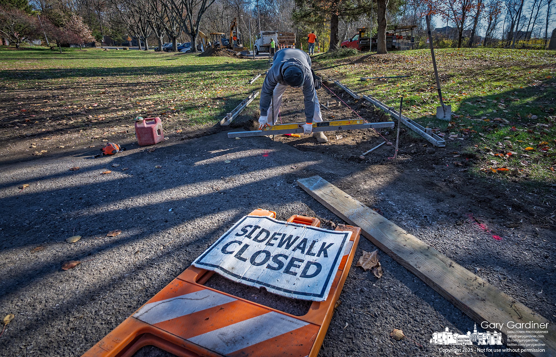 A "Sidewalk Closed" sign lies at the end of a construction site where workers are installing a new sidewalk connecting to the handicapped parking area at Alum Creek Park North in Westerville.