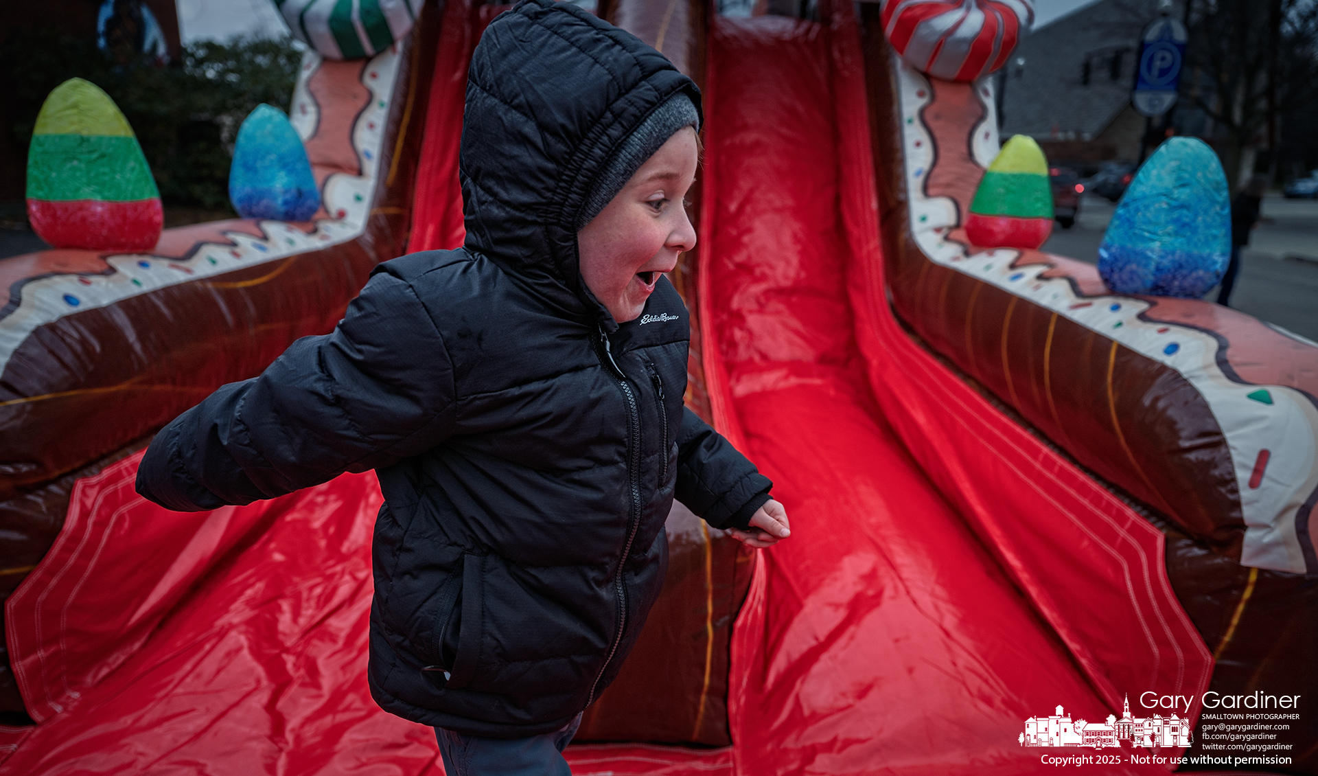 A child celebrates despite the cold after coming down the inflatable gingerbread slide in Uptown during Small Business Sunday. My Final Photo for November 30, 2025.