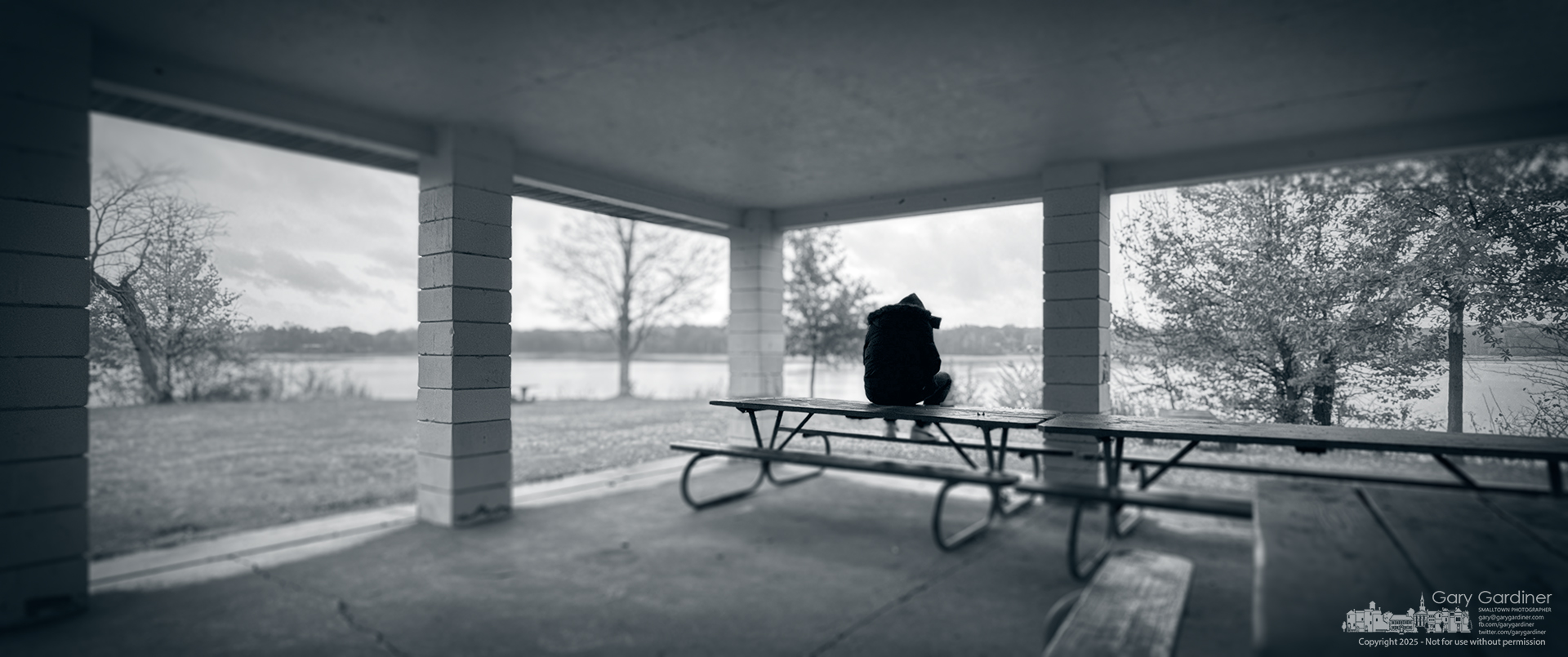A cold rain drifts across Red Bank Park while a lone figure sits on the picnic table, waiting out the weather and his thoughts in the quiet shelter of the pavilion. My Final Photo for November 18, 2025.