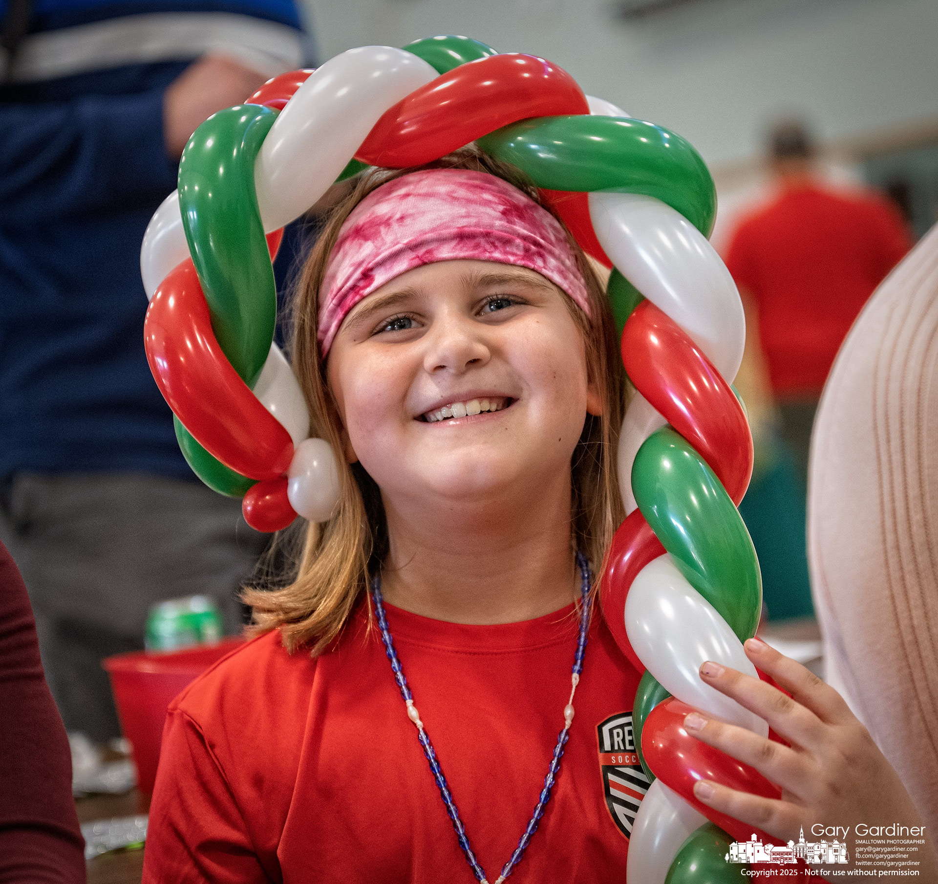 A young girl wraps herself in a balloon candy cane given to her at the St. Paul Annual Deck the Halls Christmas Bazaar on Saturday. My Final Photo for November 22, 2025.
